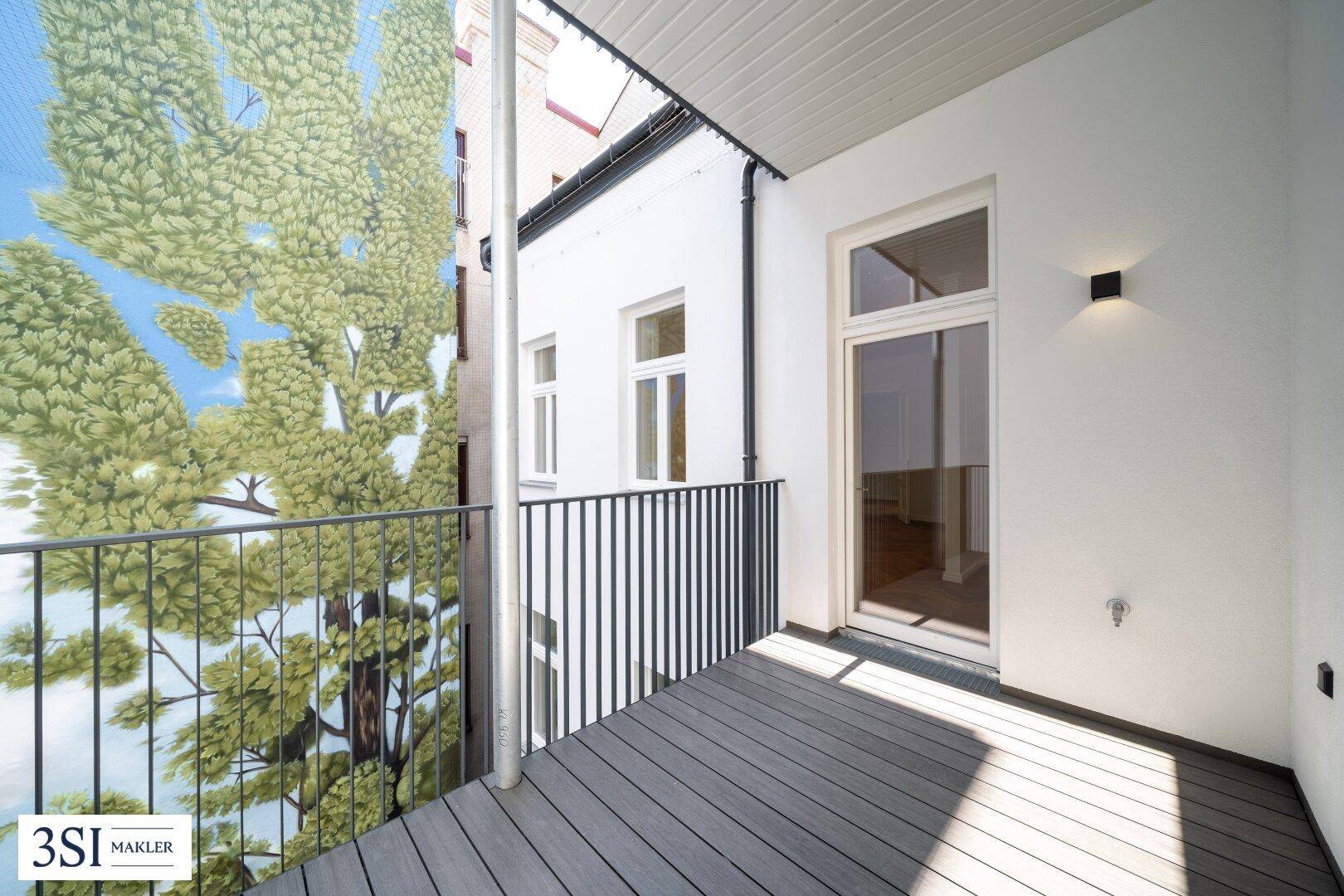 Schmaler Balkon mit Holzboden und Blick auf eine bemalte Wand mit Baummotiv.