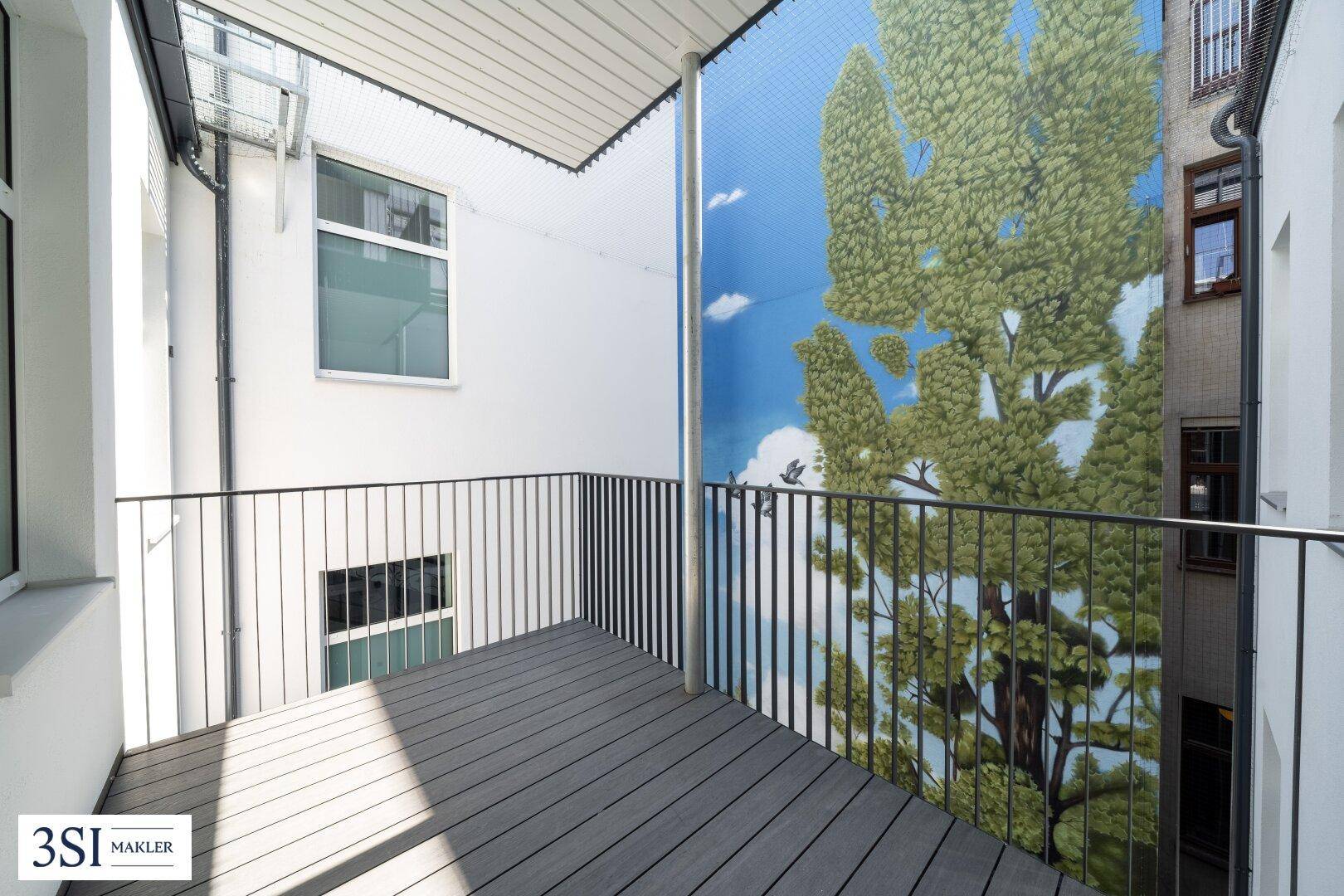 Balkon mit Holzboden und einer großen Wandmalerei, die eine grüne Landschaft darstellt.