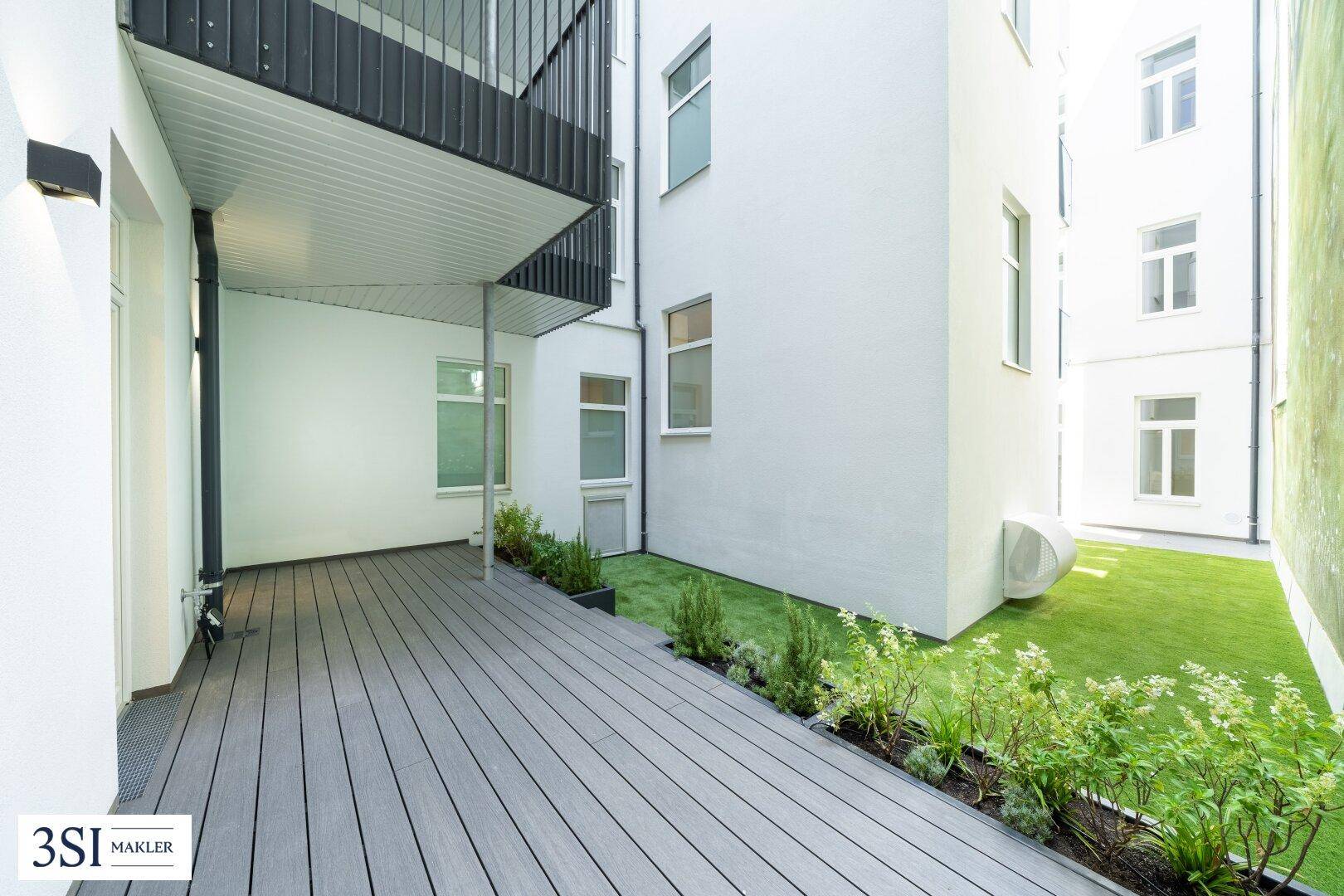 Moderne Terrasse mit Holzverbunddielen und kleinen Grünflächen, ideal für entspannte Stunden im Freien.