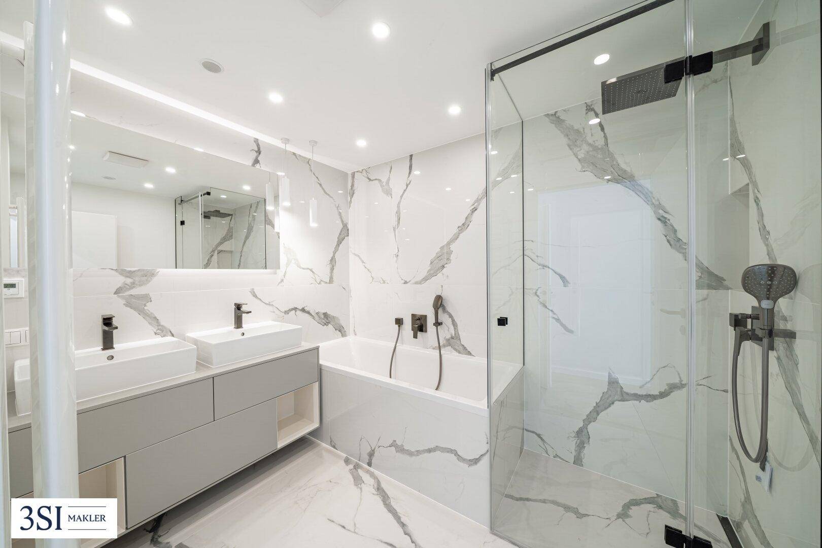 Modernes Badezimmer mit Marmoroptikfliesen, Doppelwaschbecken, Badewanne und begehbarer Dusche.