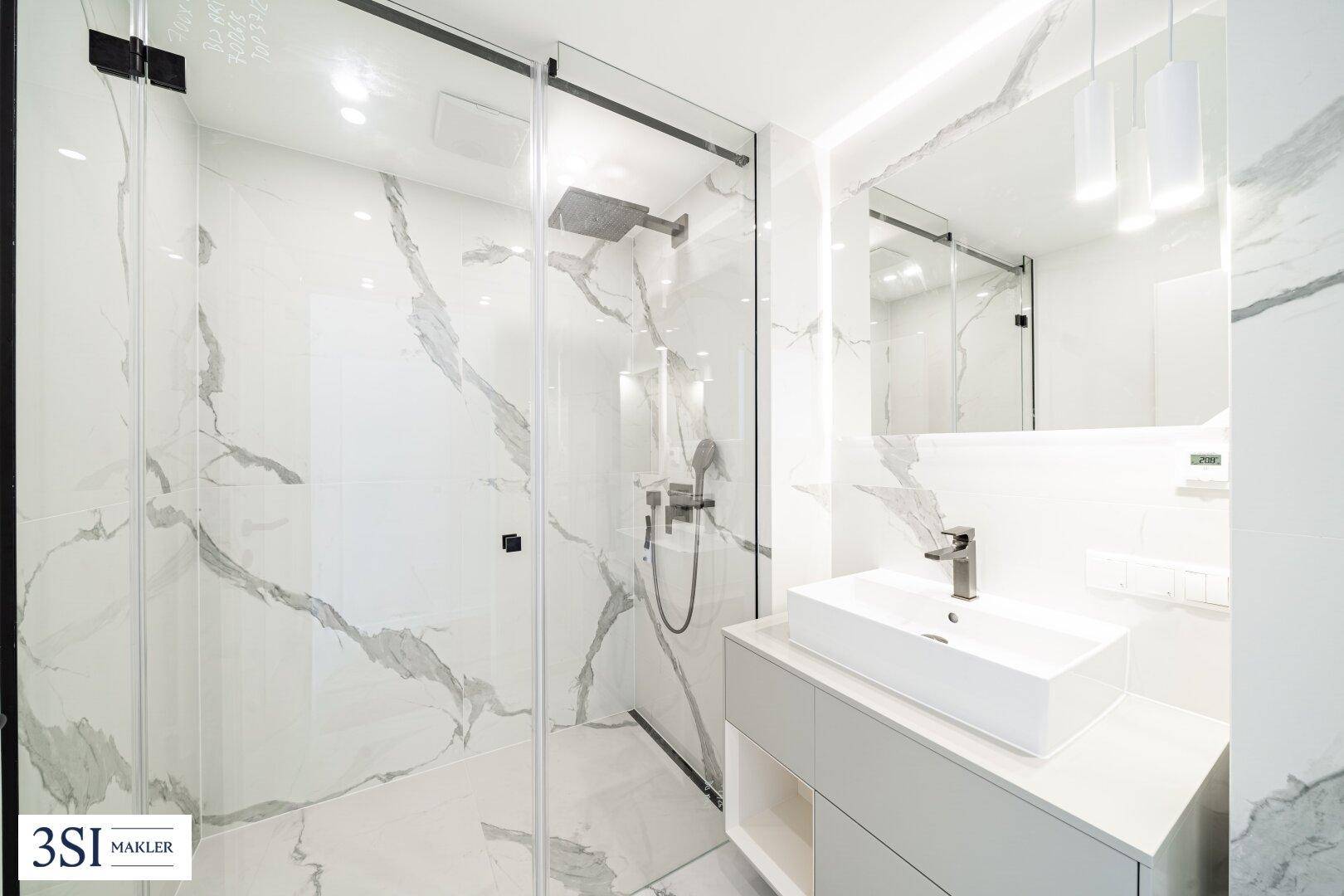 Elegantes Badezimmer mit Marmoroptikfliesen, modernem Waschtisch und begehbarer Dusche.