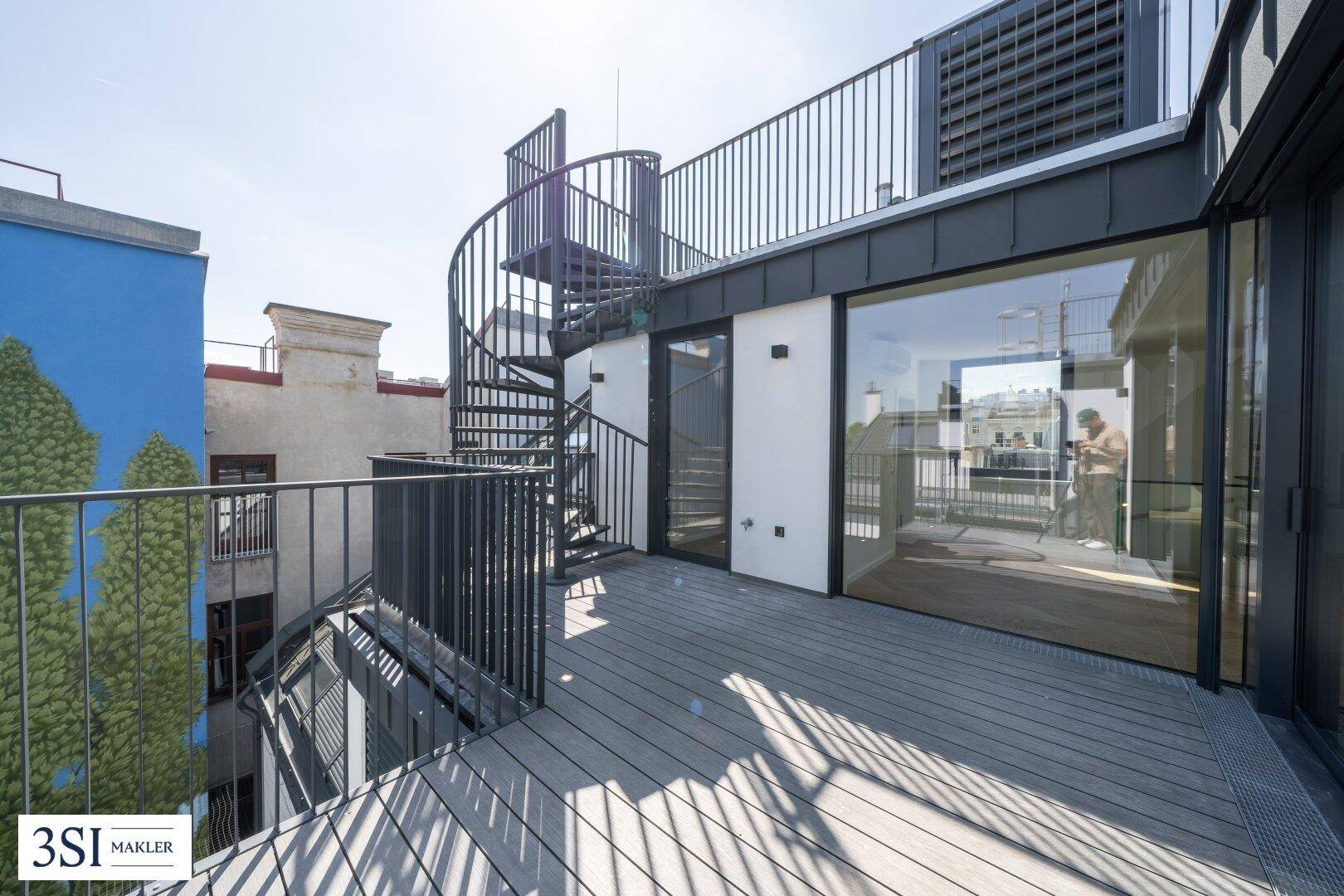 Geräumige Dachterrasse mit Holzoptik-Boden und Wendeltreppe zur oberen Ebene.
