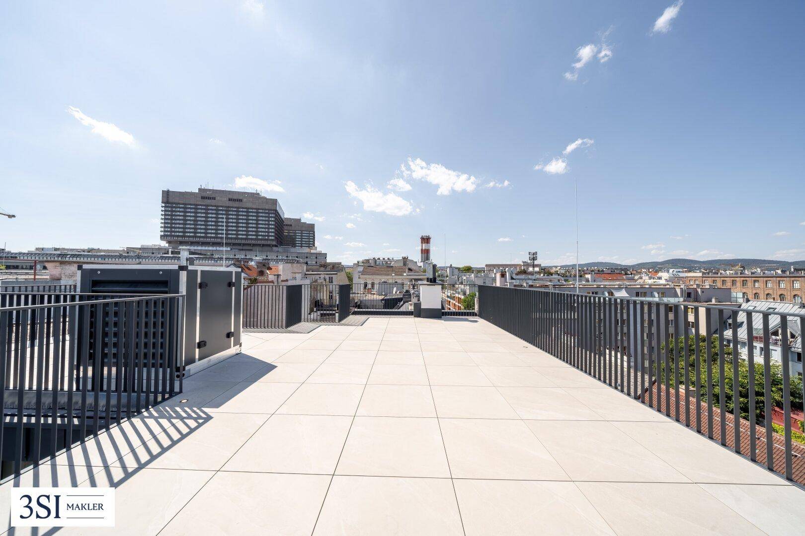 Weitläufige Dachterrasse mit Fliesenboden und Panoramablick über die Stadt.