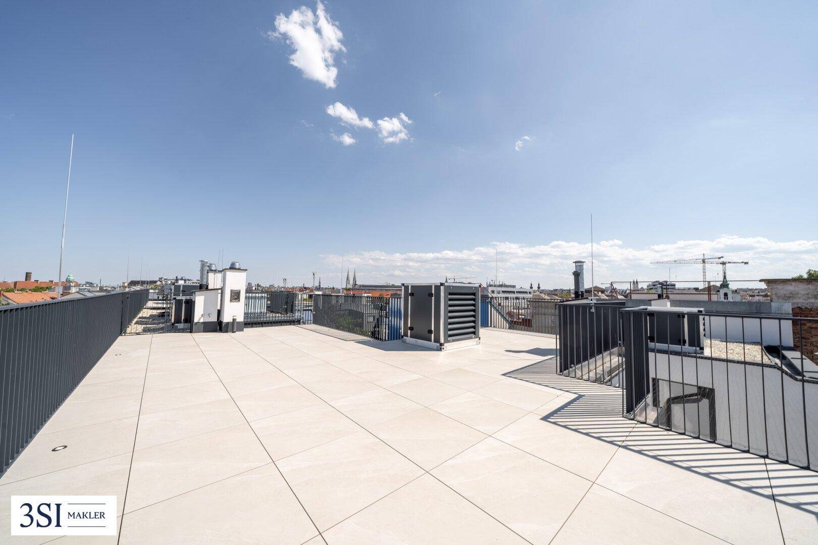 Offene Dachterrasse mit weitem Blick über die Dächer der Stadt und den Himmel.