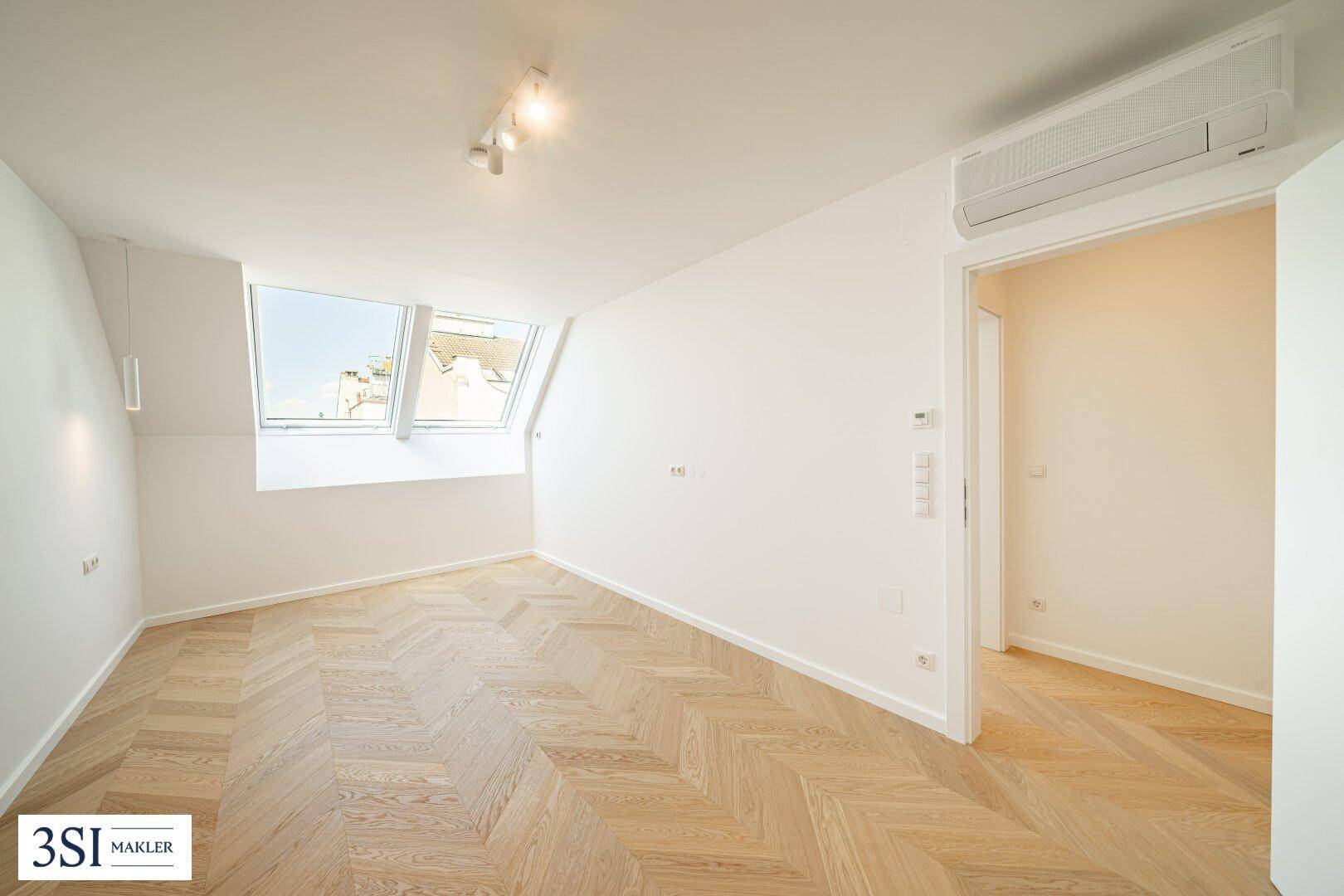 Helles Schlafzimmer mit Fischgrätparkett, Dachfenstern und Klimaanlage.