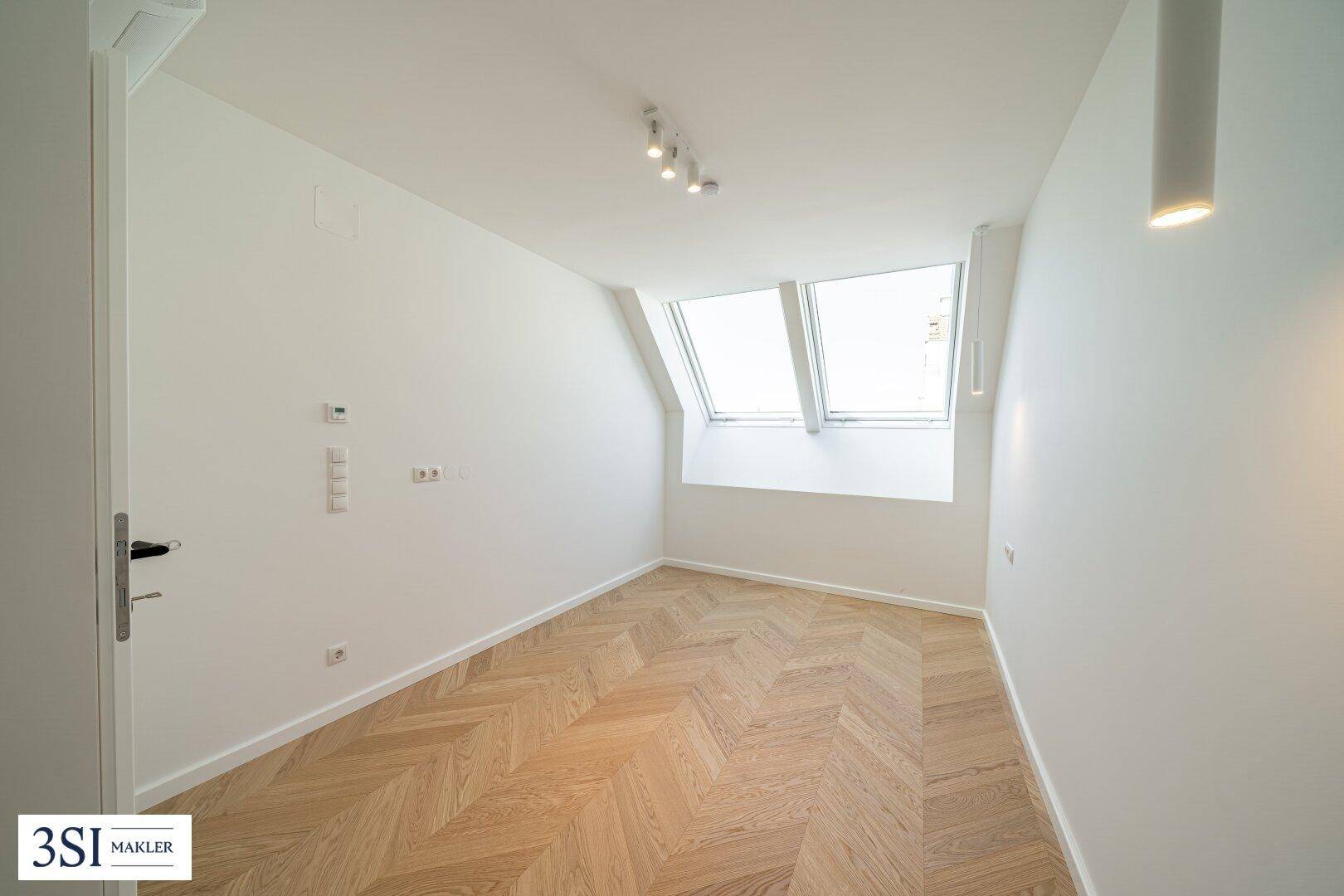 Gemütliches Schlafzimmer mit schrägen Wänden, Dachfenstern und hellem Fischgrätparkett.
