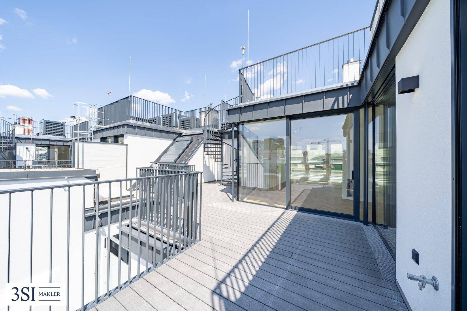 Große Dachterrasse mit Holzbelag, Metallgeländer und Wendeltreppe zu einer weiteren Ebene.