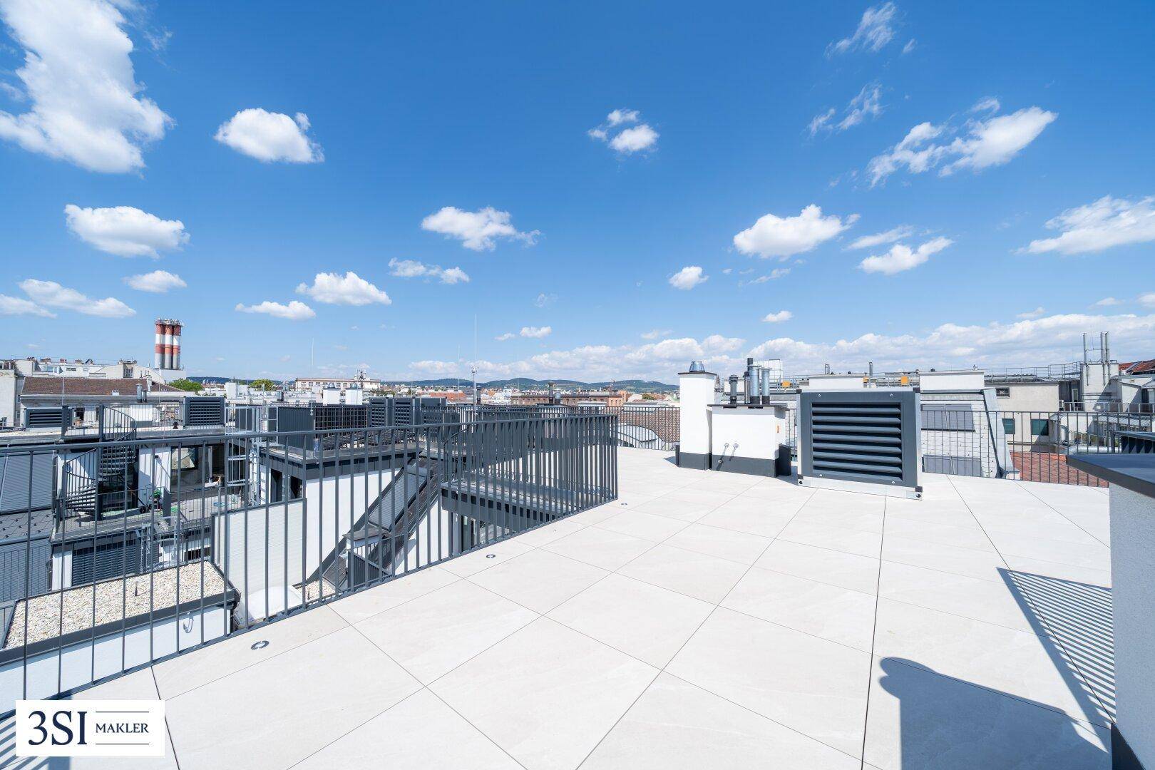 Weitläufige Dachterrasse mit hellen Fliesen und Panoramablick über die Stadt und die Hügel.