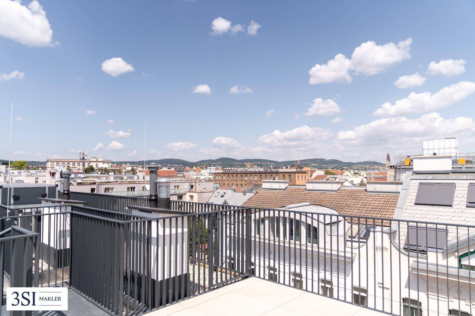 Dachterrasse mit weitem Blick über die Dächer der Stadt und die umliegende Landschaft.