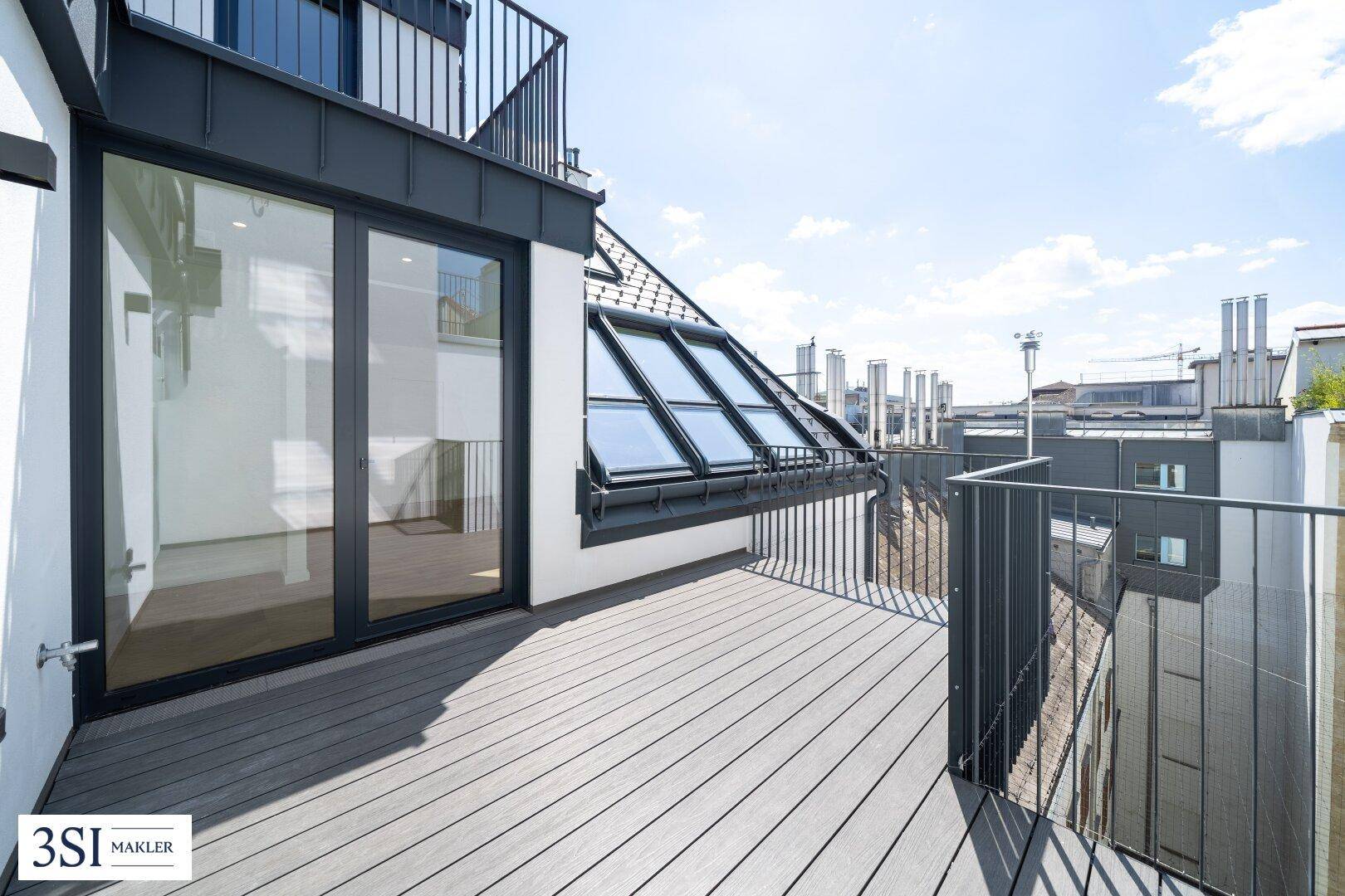 Großer Balkon mit Holzdielenboden und Blick über die Dächer der Stadt.