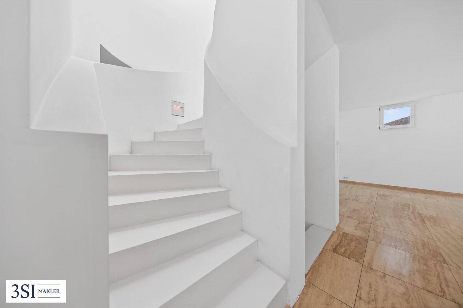 Moderne, geschwungene Treppe in Weiß, die die verschiedenen Ebenen des Hauses verbindet.
