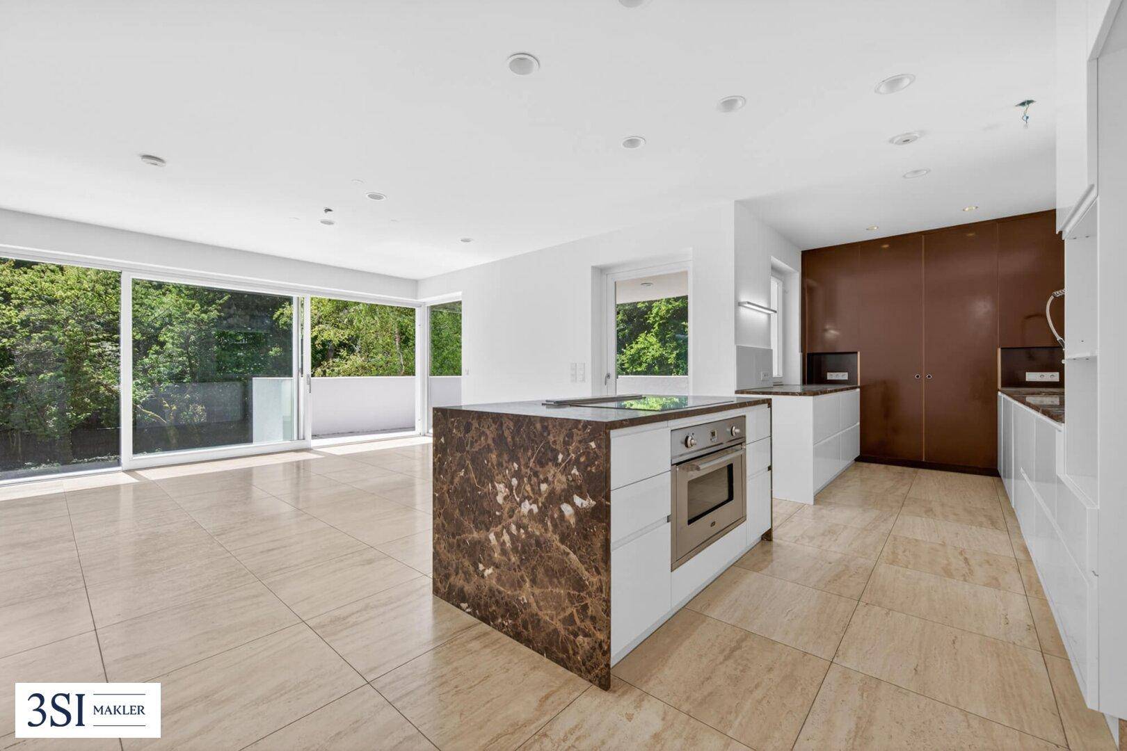 Offene moderne Küche mit Kochinsel, integriertem Backofen und Zugang zum Balkon.