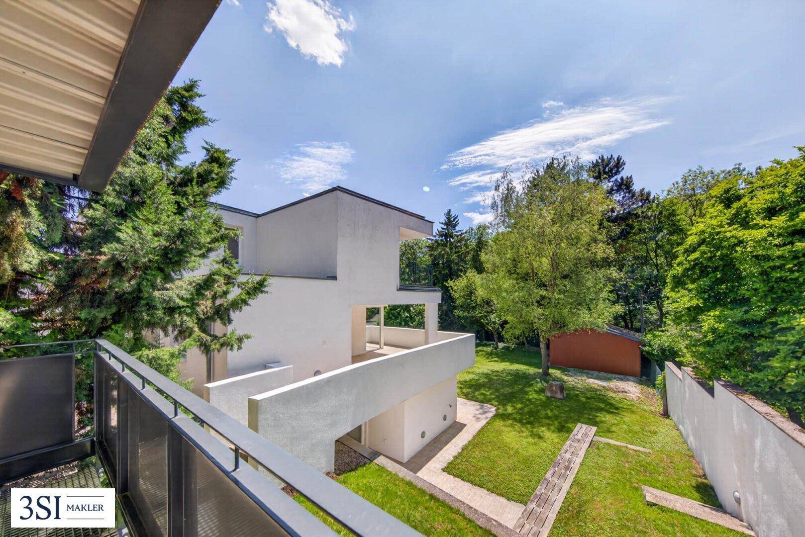 Balkon mit Metallgeländer und weitem Blick über den Garten und die grüne Umgebung.
