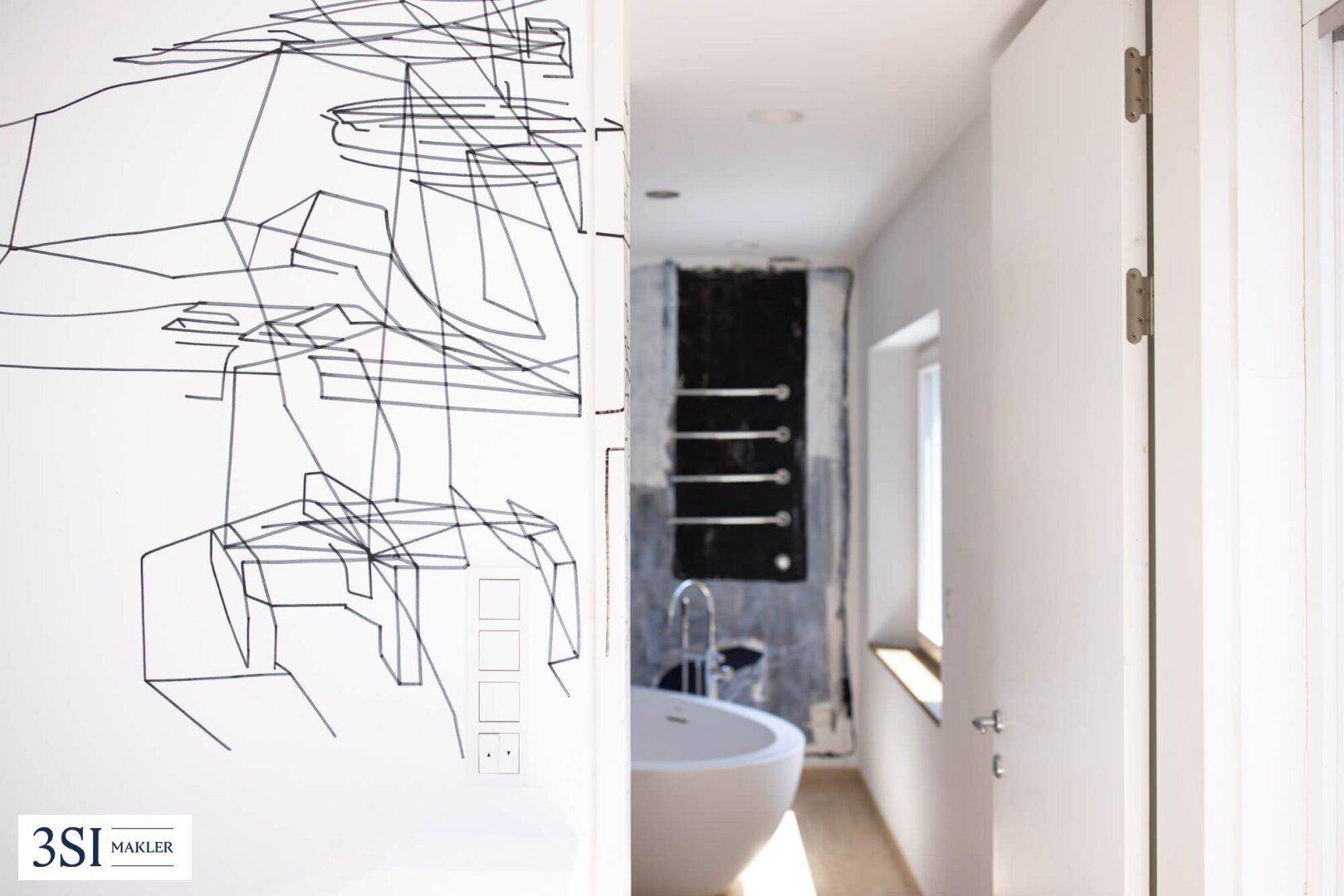 Flur mit moderner Wandkunst und Blick auf das Badezimmer mit freistehender Badewanne.