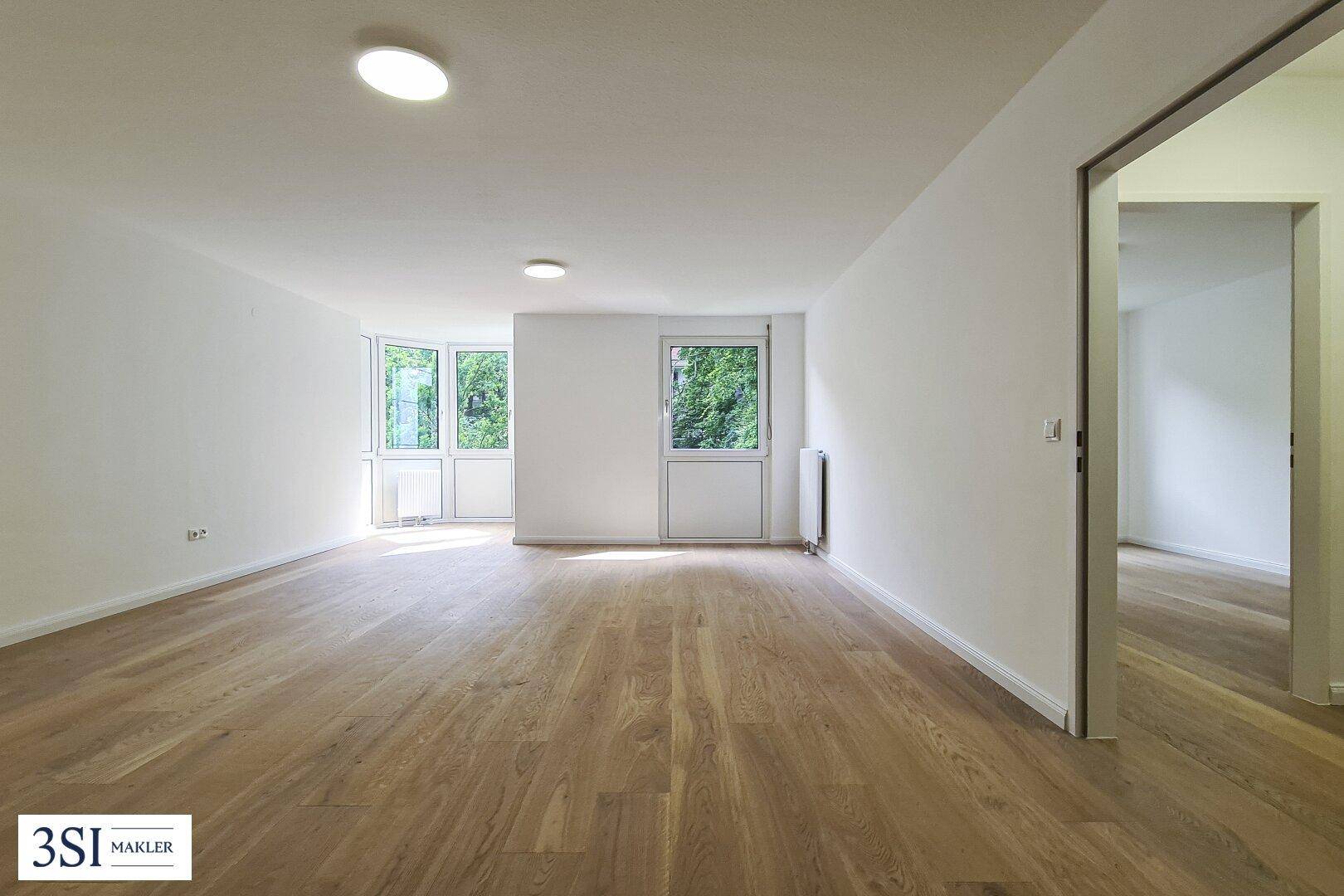 Lichtdurchfluteter Raum mit hellem Holzboden, weißen Wänden und Zugang zu einem Außenbereich.