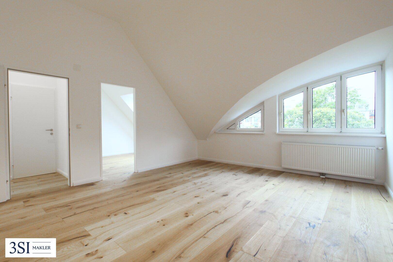 Helles Zimmer mit modernem Holzboden, Dachschrägen und Fenstern für natürliche Belichtung.