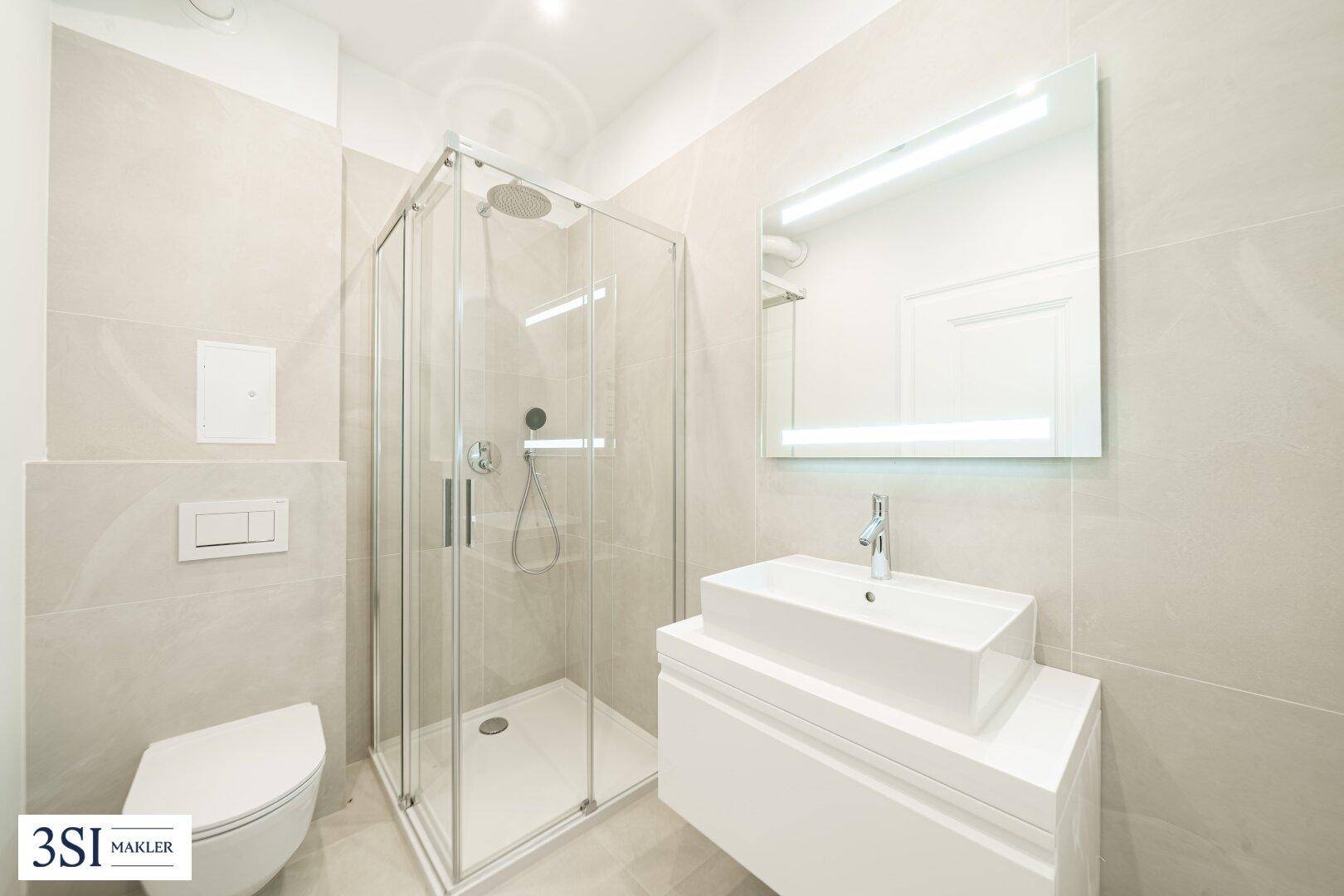 Modernes Badezimmer mit Duschkabine, wandhängendem WC und eleganten hellen Fliesen.