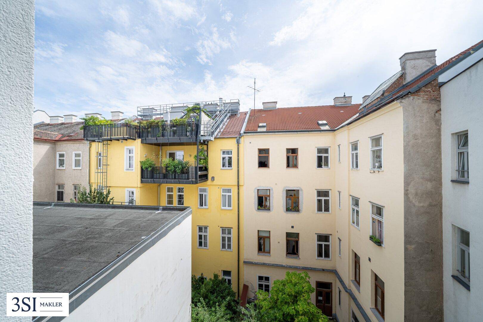 Blick auf den begrünten Innenhof mit mehreren Gebäuden und Dachterrassen.