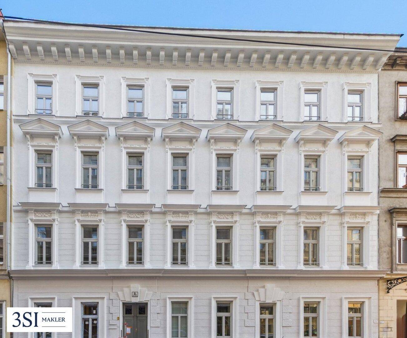 Klassische Altbaufassade mit reich verzierten Fenstern und eleganten Stuckelementen.
