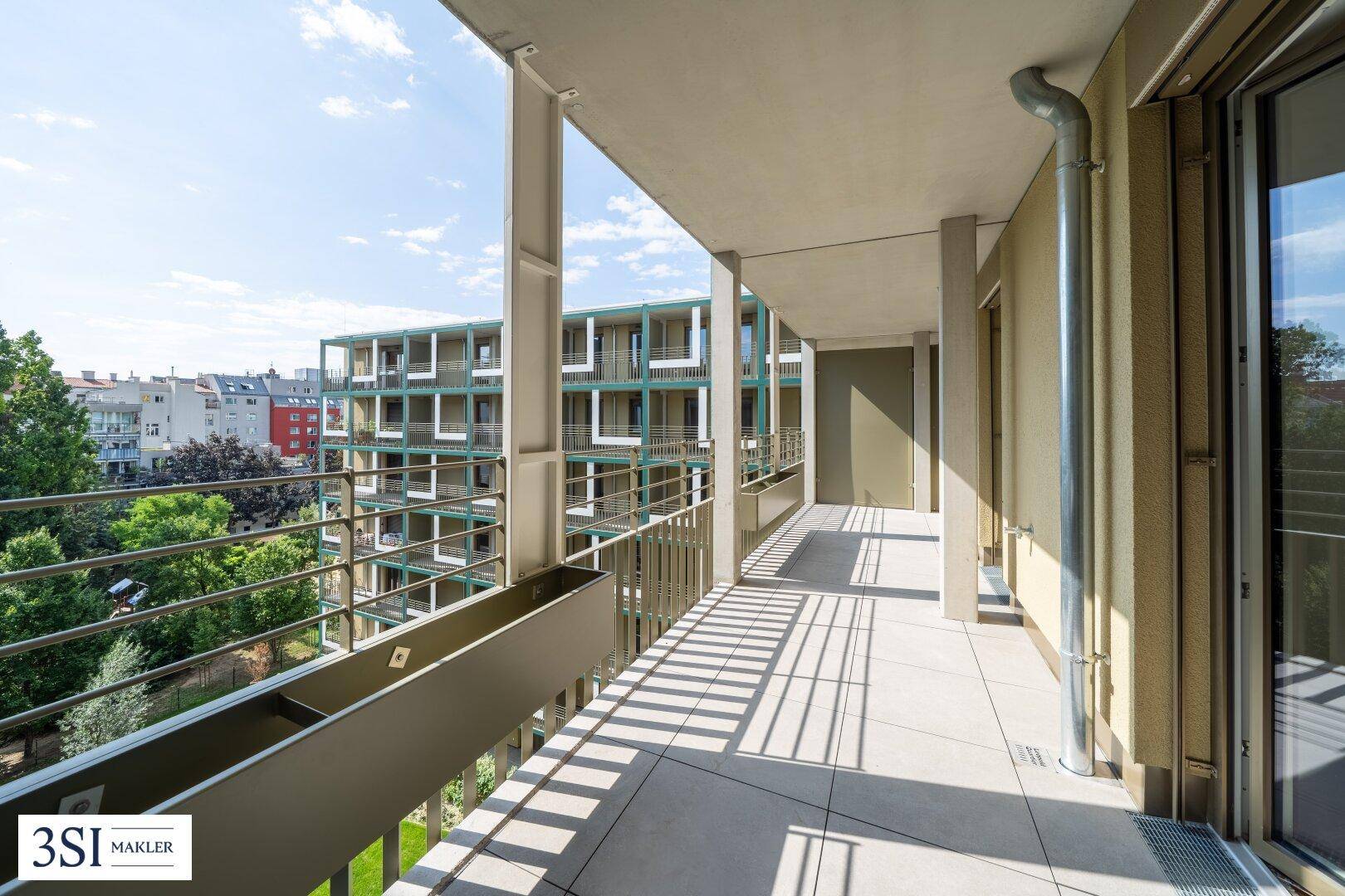 Langer, schmaler Balkon mit Fliesenboden und Blick auf den Innenhof und die umliegenden Gebäude.