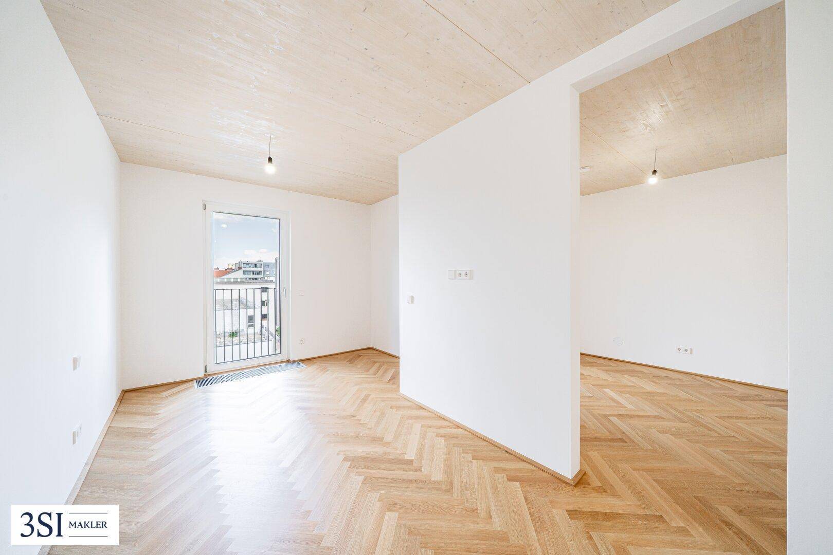 Geräumiger, heller Raum mit Holzdecken und Fischgrätparkett, ideal für individuelle Gestaltung.