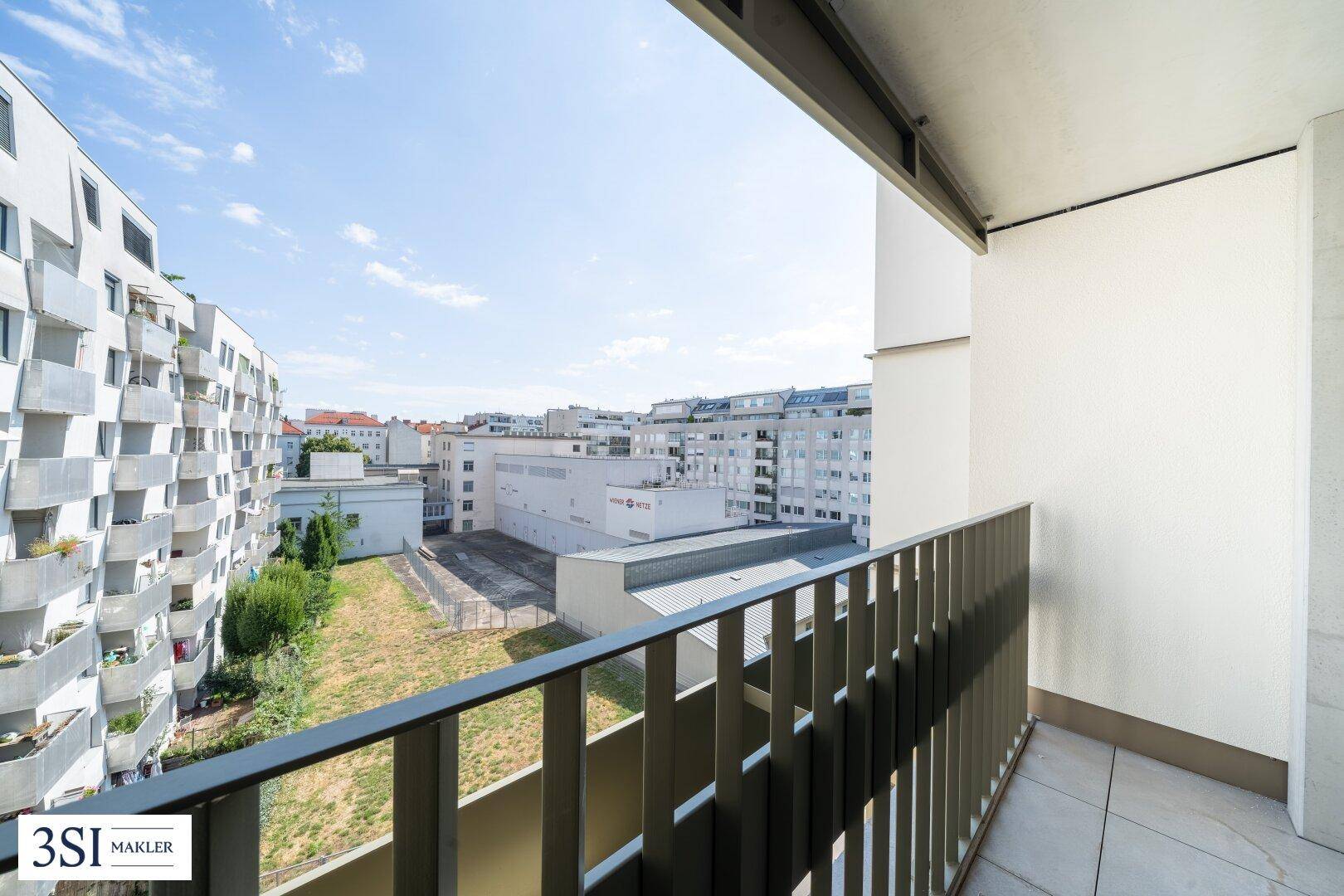 Balkon mit Blick auf die umliegenden Gebäude und eine Grünfläche.