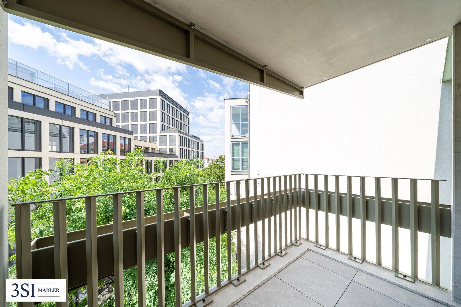 Balkon mit Blick auf moderne Gebäude und grüne Bäume, ideal für entspannte Stunden im Freien.