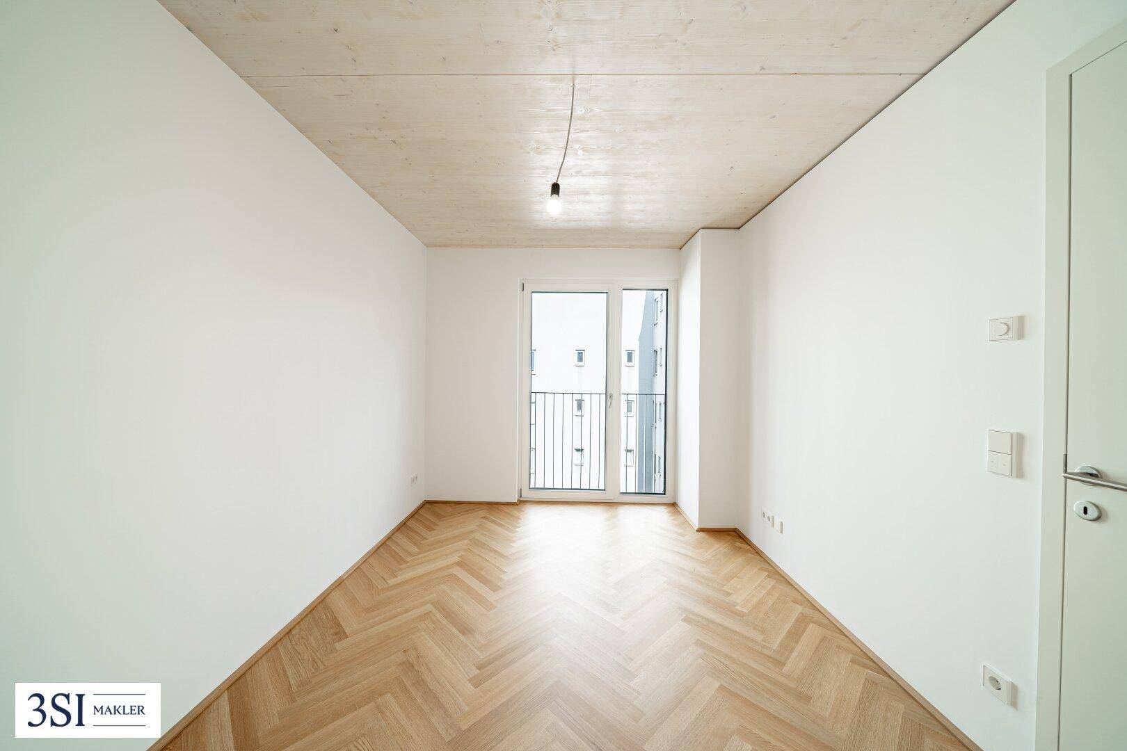 Helles Schlafzimmer mit Fischgrätparkett, Holzbalkendecke und Zugang zu einem französischen Balkon.