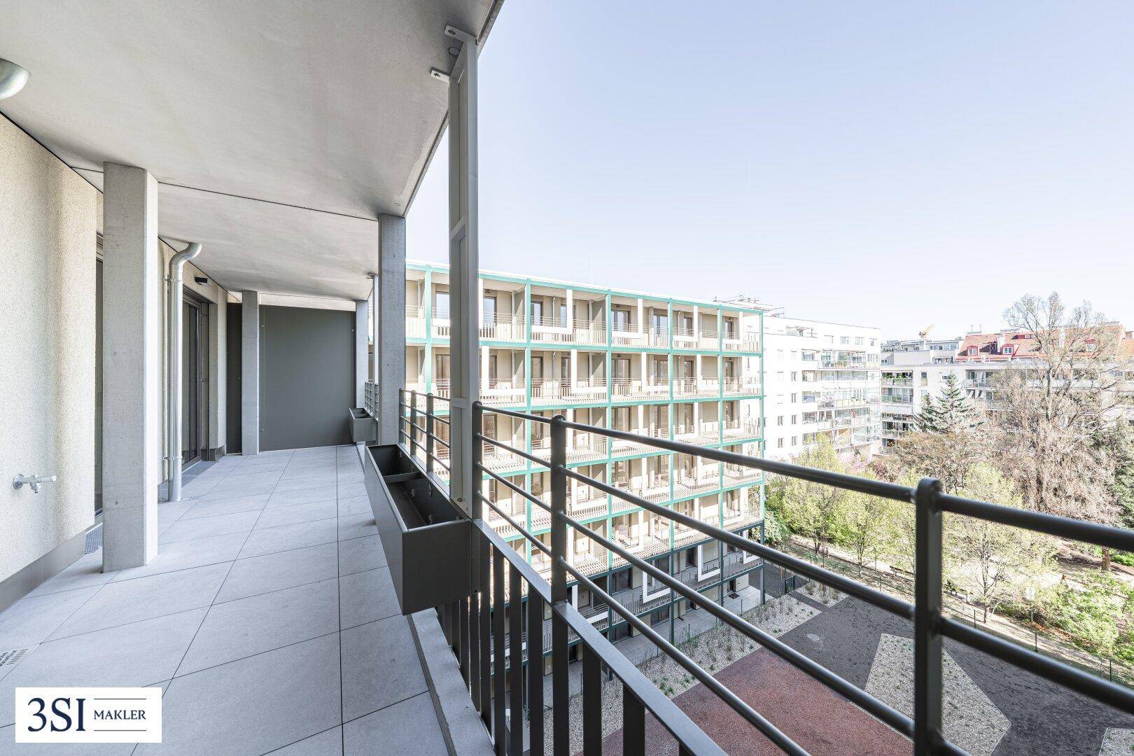 Balkon mit weitem Blick über die Stadt, Bäume und angrenzende Wohngebäude.