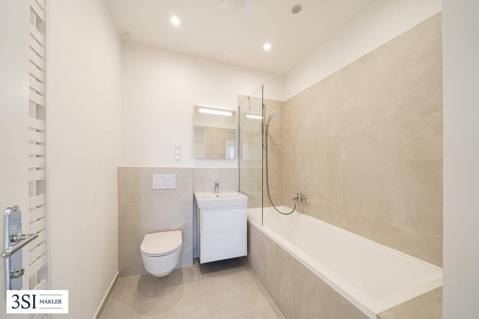 Modernes Badezimmer mit Badewanne, Dusche und beheiztem Handtuchhalter.