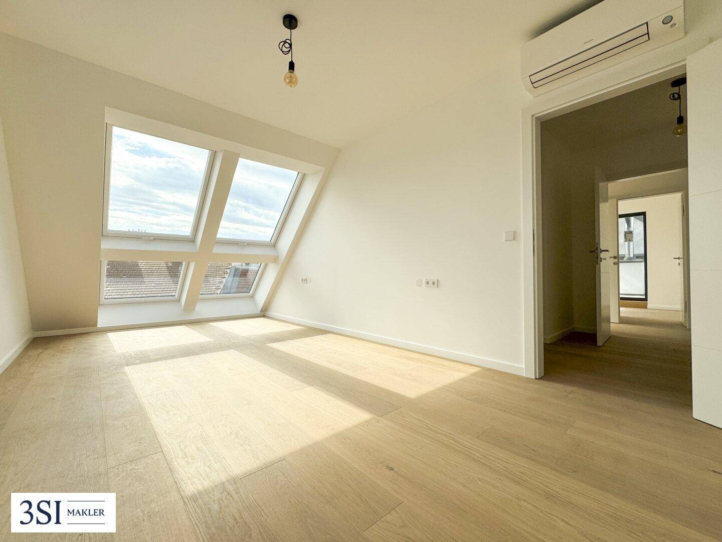 Lichtdurchfluteter Raum mit Holzboden, Dachschrägen und Klimaanlage, ideal für Schlaf- oder Arbeitszimmer.