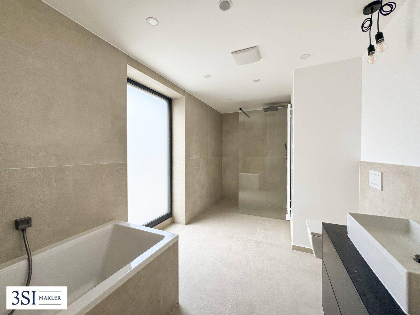 Modernes Badezimmer mit Badewanne, begehbarer Dusche, Doppelwaschbecken und großformatigen Fliesen.