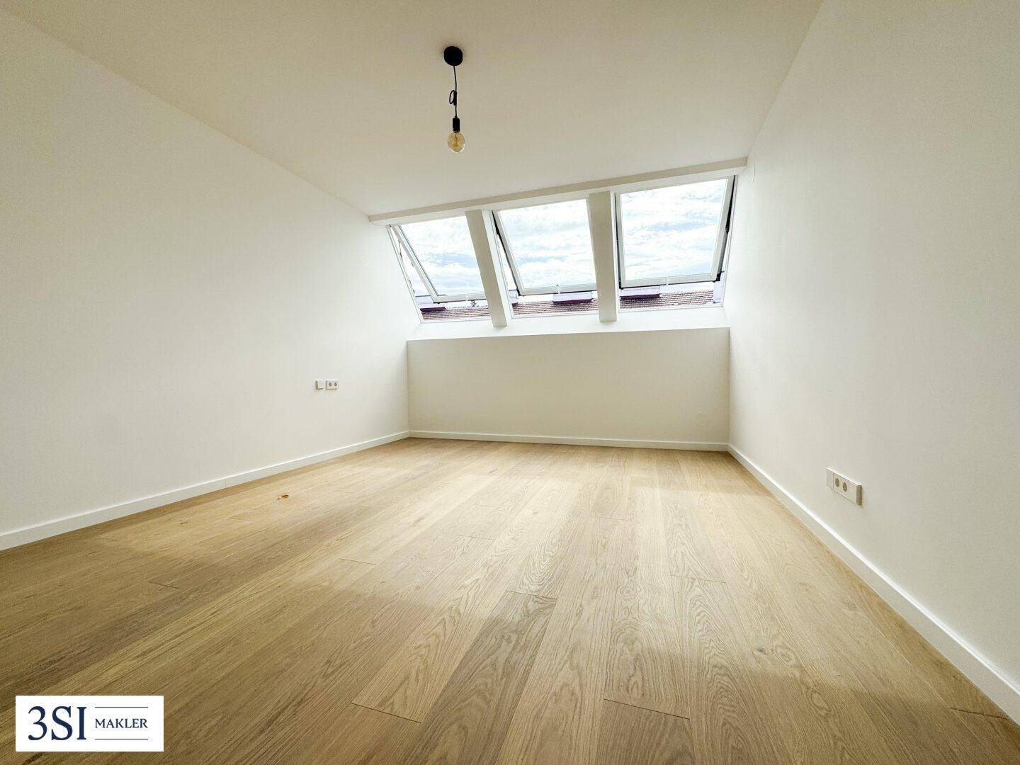 Lichtdurchfluteter Raum mit Holzboden, Dachschrägen und drei Dachfenstern für optimale Belichtung.
