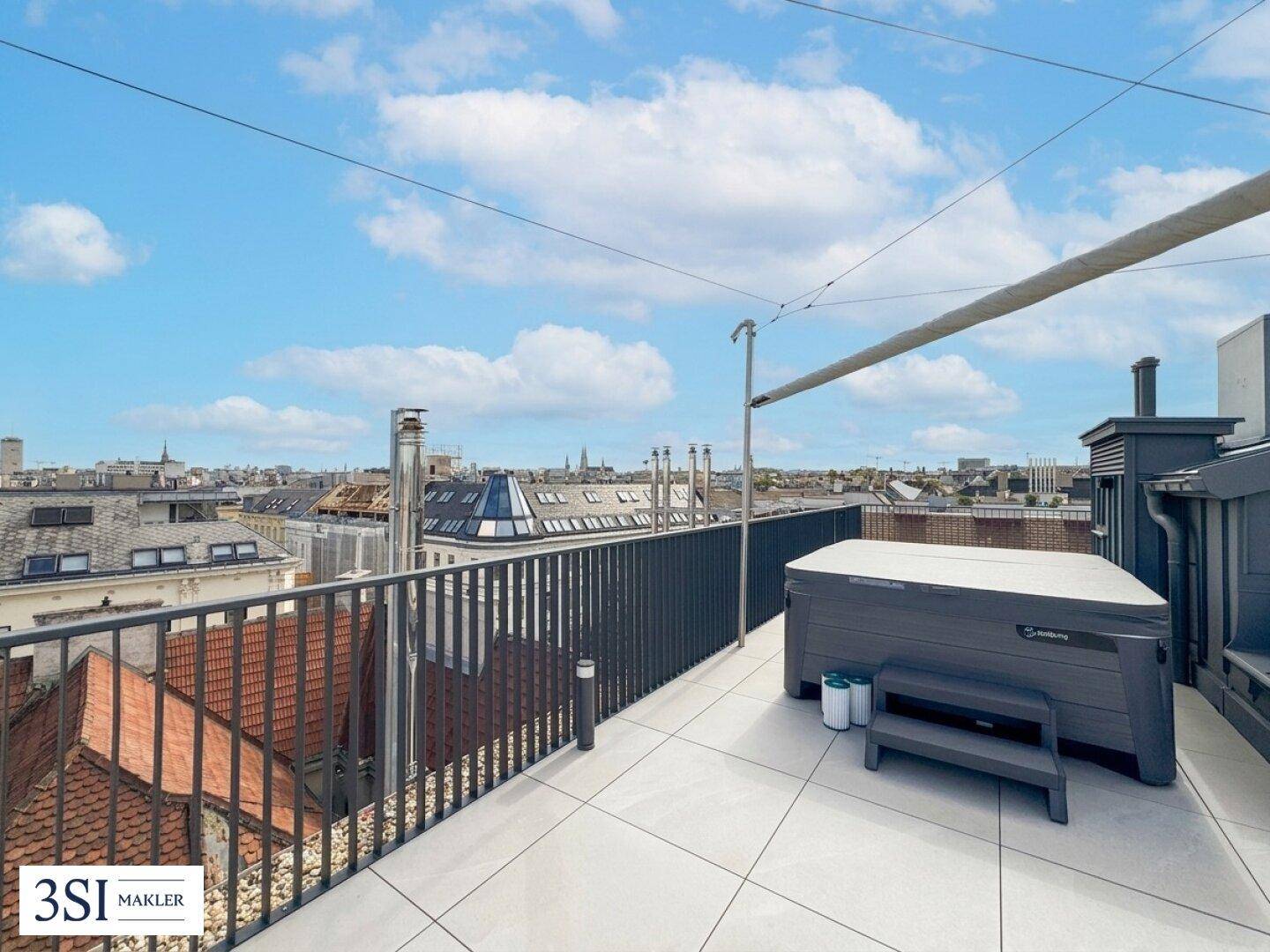 Weitläufige Dachterrasse mit Whirlpool und Panoramablick über die Stadt unter blauem Himmel.