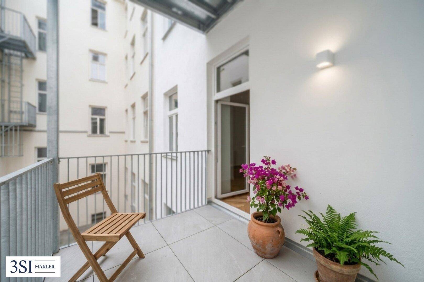Kleiner Balkon mit Fliesenboden und Blick auf den Innenhof, ideal für Pflanzen.