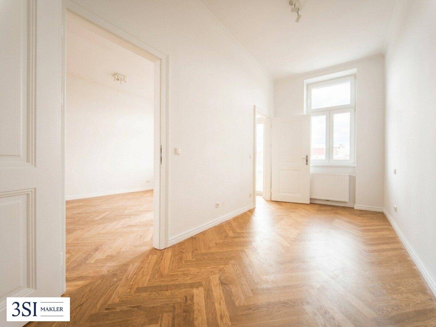 Helles Zimmer mit Fischgrätparkett und Fenster, das sich ideal als Schlaf- oder Arbeitszimmer eignet.