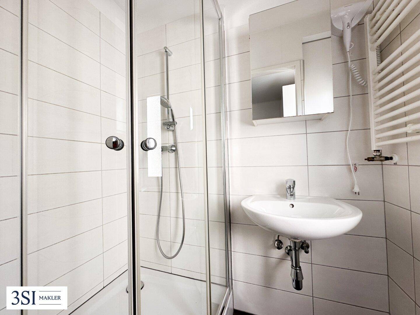 Modernes Badezimmer mit Duschkabine, Einzelwaschbecken und Handtuchheizkörper.