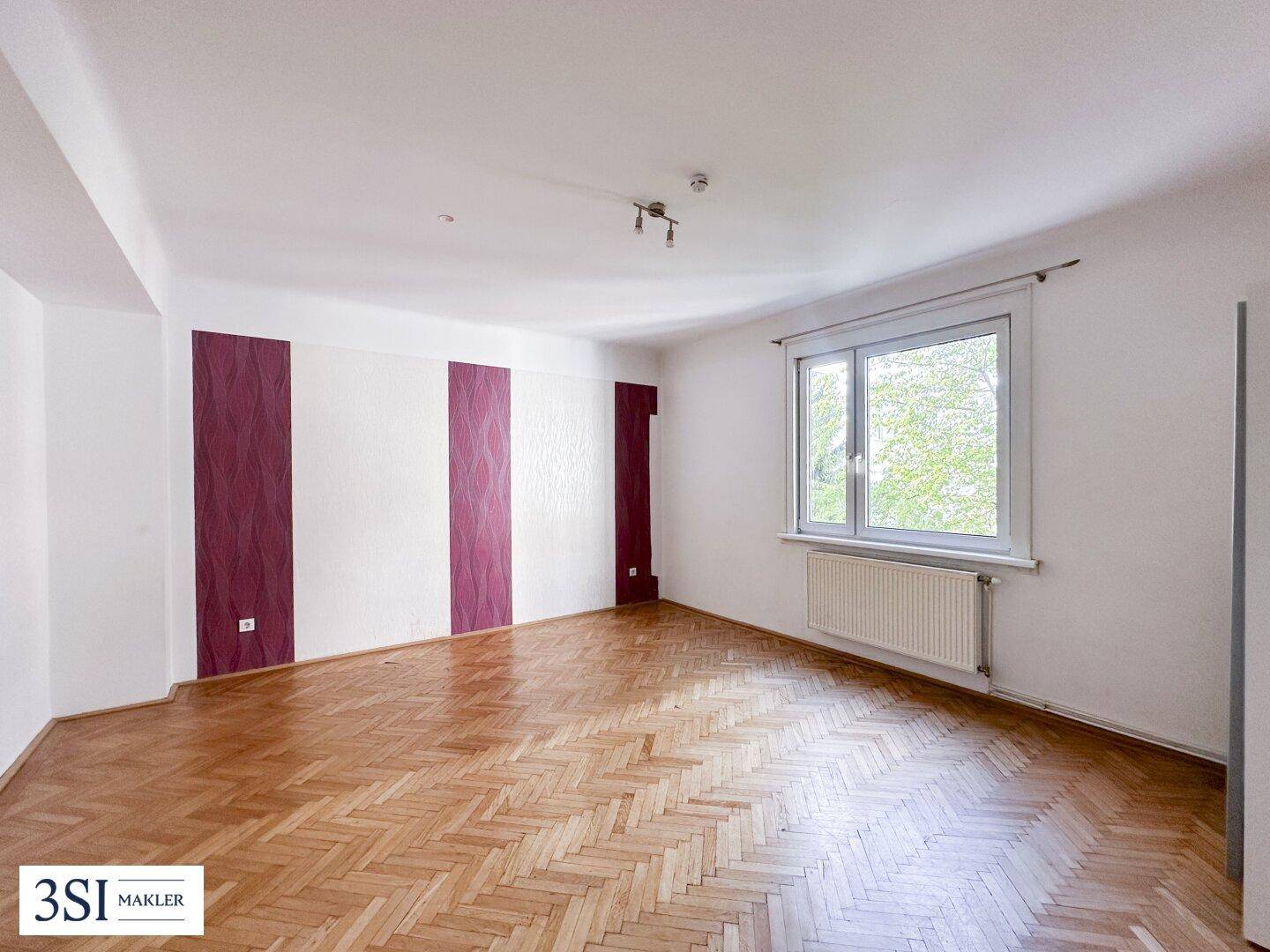 Helles Wohnzimmer mit Fischgrätparkettboden und dekorativen Akzentwänden.