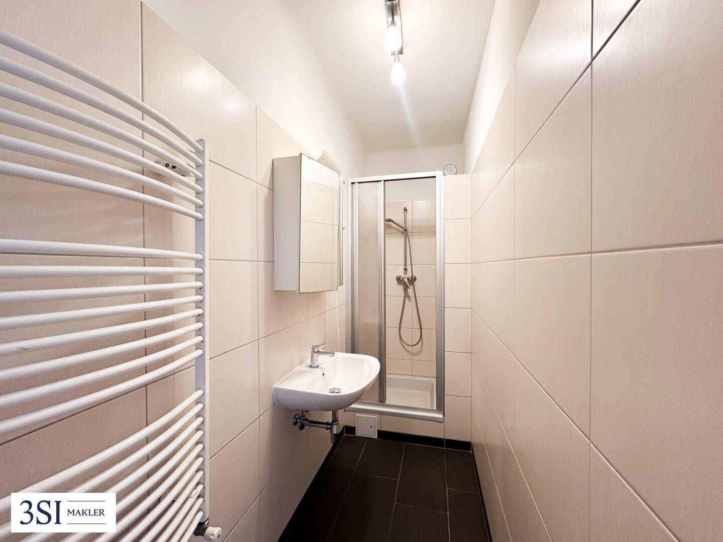 Modernes Badezimmer mit Duschkabine, Einzelwaschbecken und beheiztem Handtuchhalter.