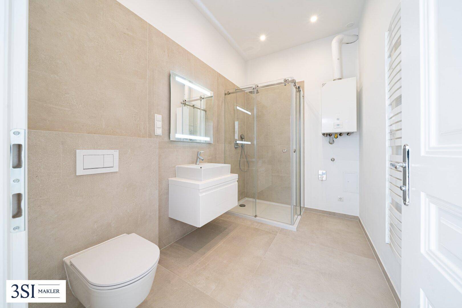 Modernes Badezimmer mit beigen Fliesen, Glasdusche, wandhängendem WC und Handtuchheizkörper.