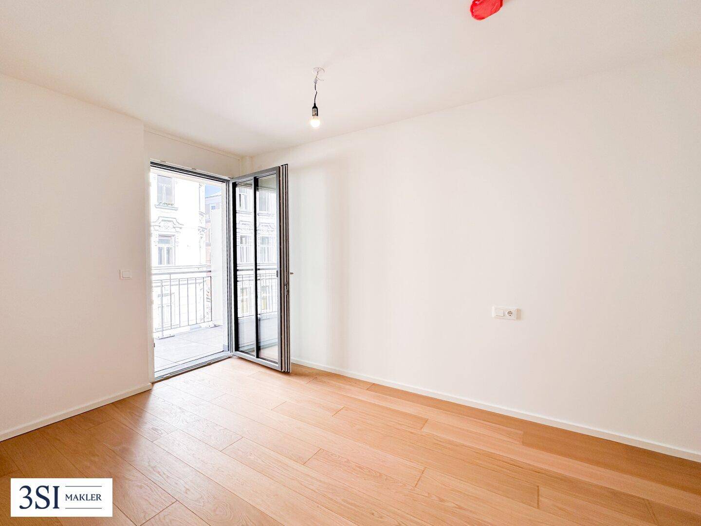 Geräumiges, helles Zimmer mit Holzboden und weit geöffneter Balkontür, bereit zur Einrichtung.