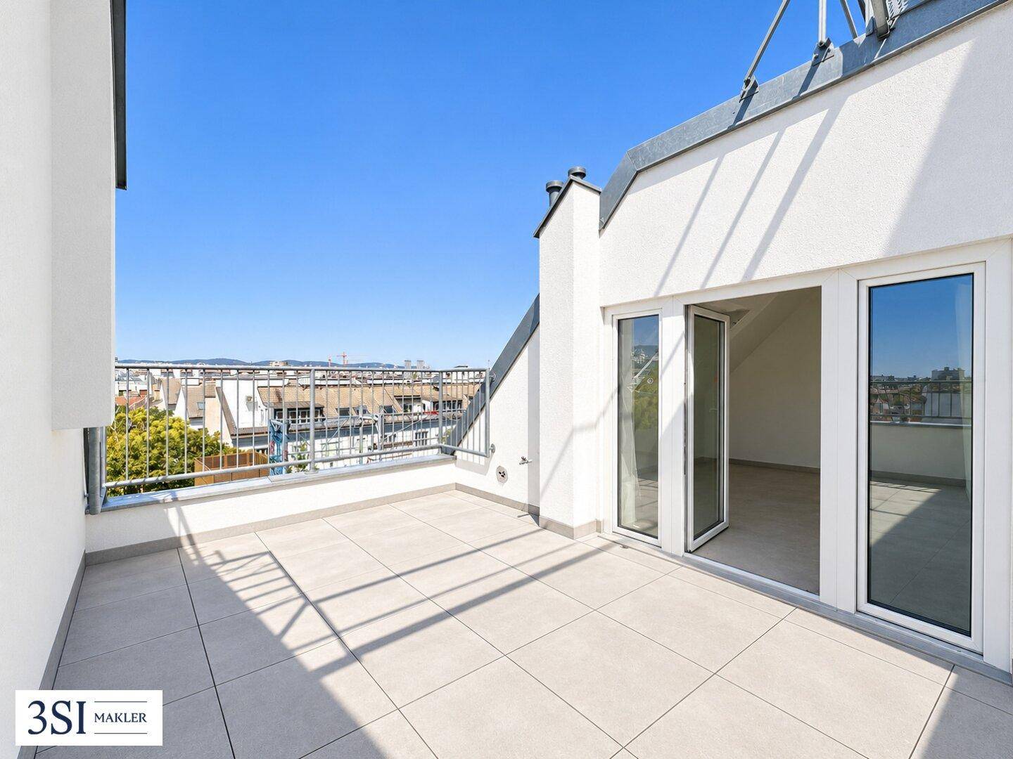Geräumige Dachterrasse mit Fliesenboden und weitem Blick über die umliegende Stadtlandschaft.