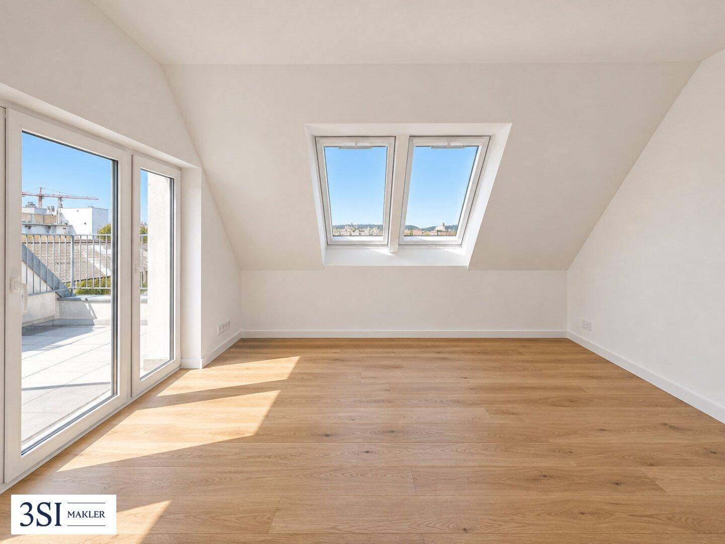 Heller Raum im Dachgeschoss mit Holzboden, großen Fenstern und Zugang zur Terrasse.