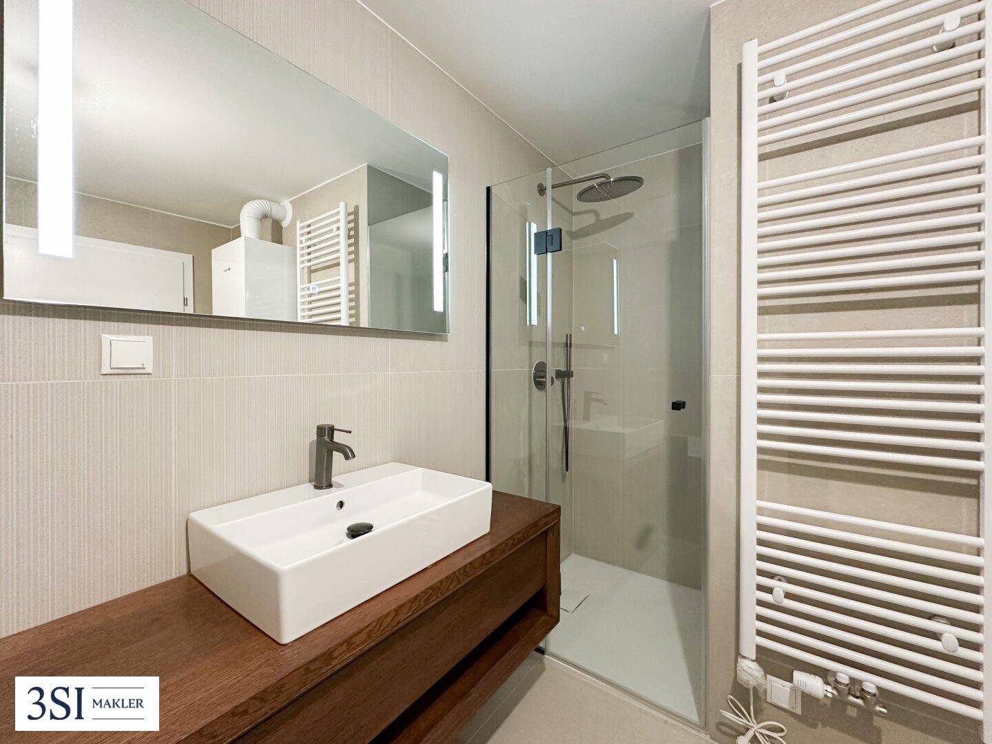 Modernes Badezimmer mit begehbarer Dusche, Einzelwaschbecken und beheiztem Handtuchhalter.