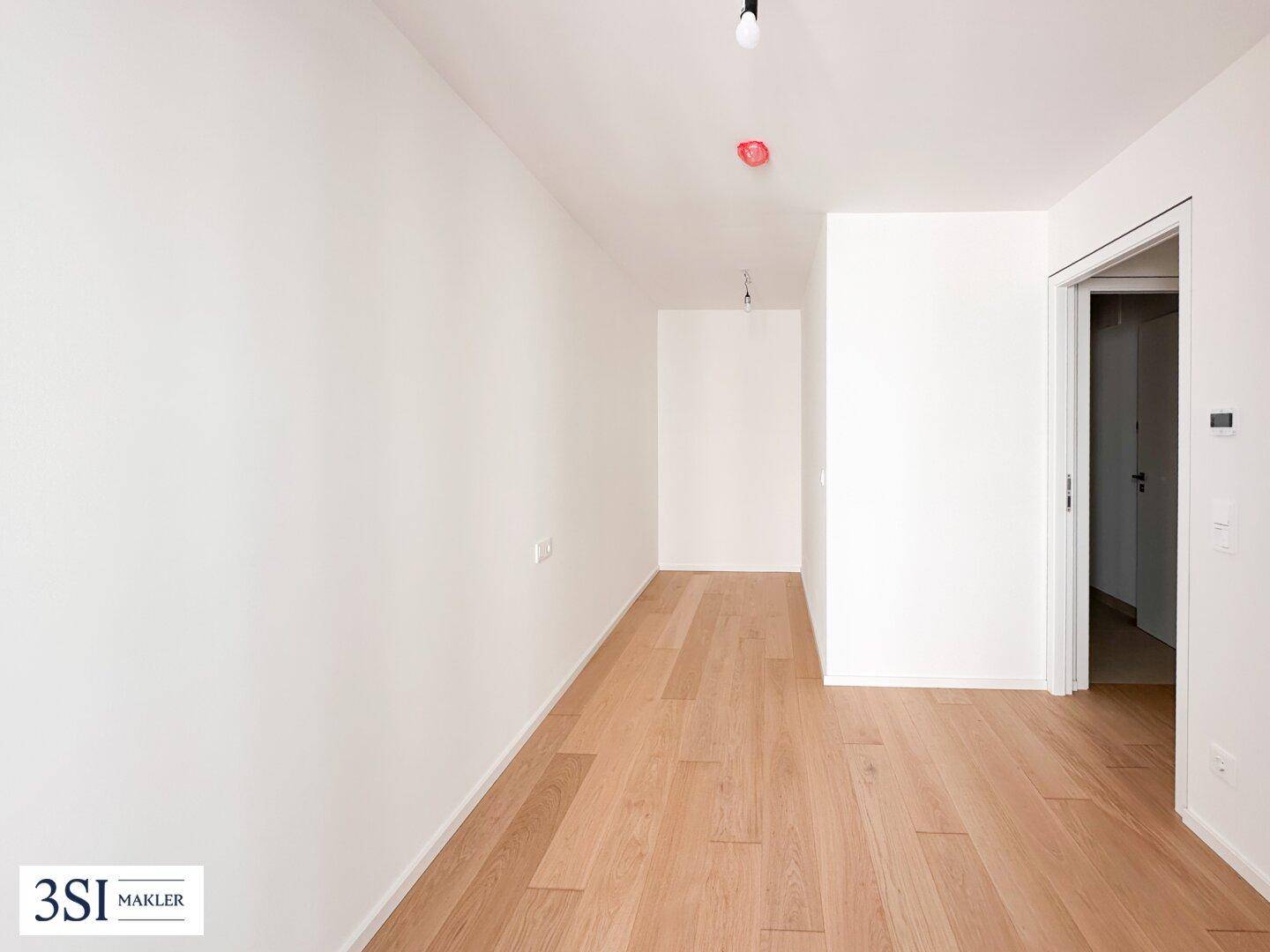 Heller Flur mit Holzboden, der verschiedene Räume der Wohnung verbindet.