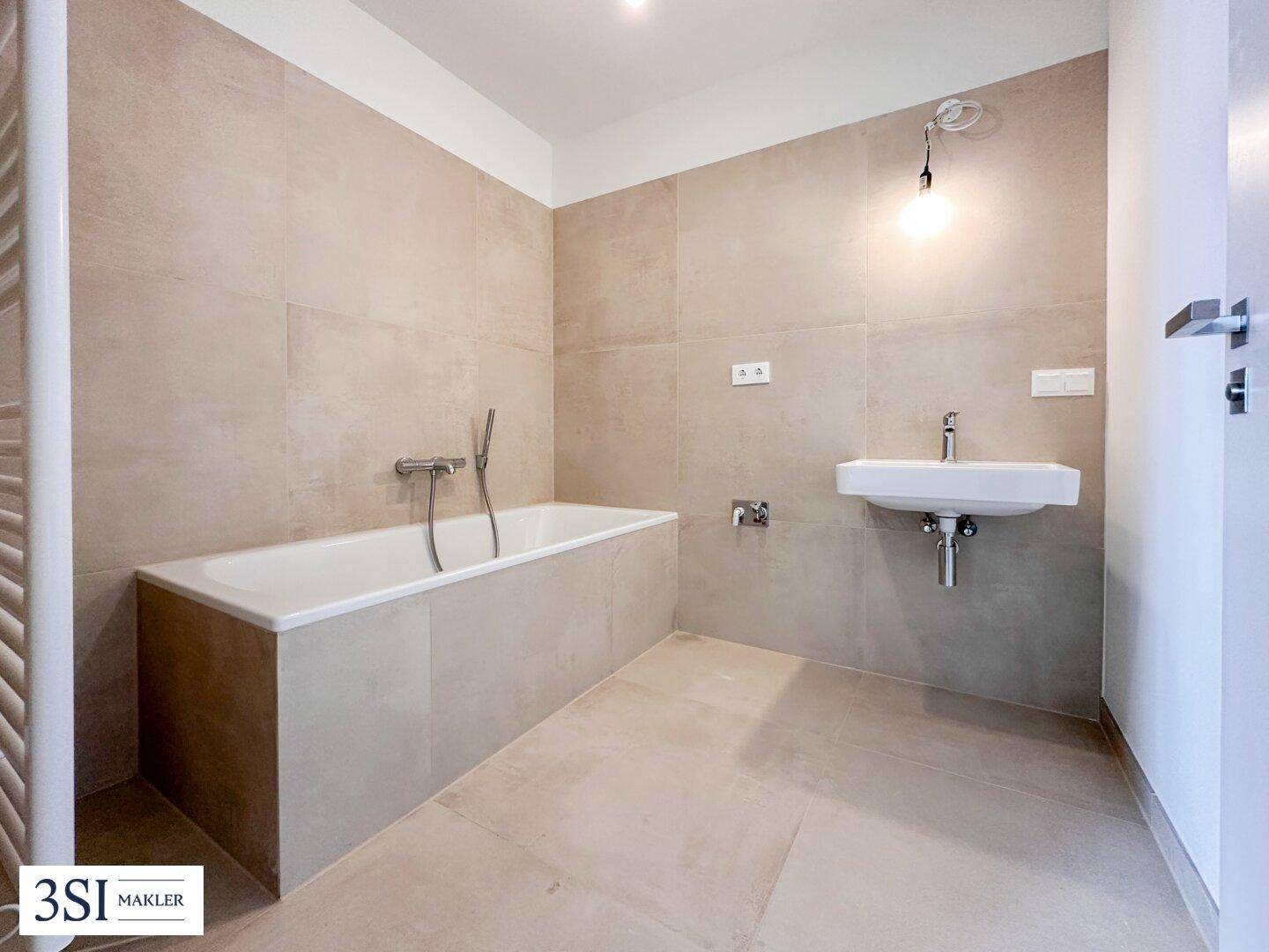 Modernes Badezimmer mit Badewanne, Einzelwaschbecken und beigefarbenen Fliesen.