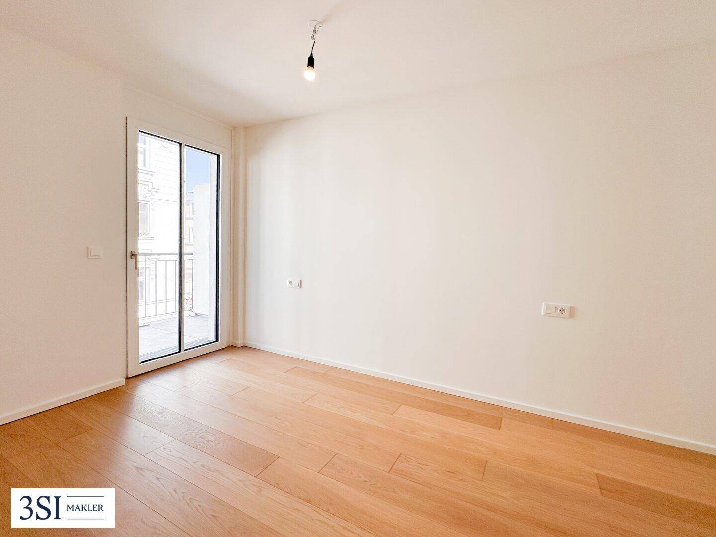 Geräumiges Schlafzimmer mit hellem Holzboden und direktem Zugang zum Balkon.