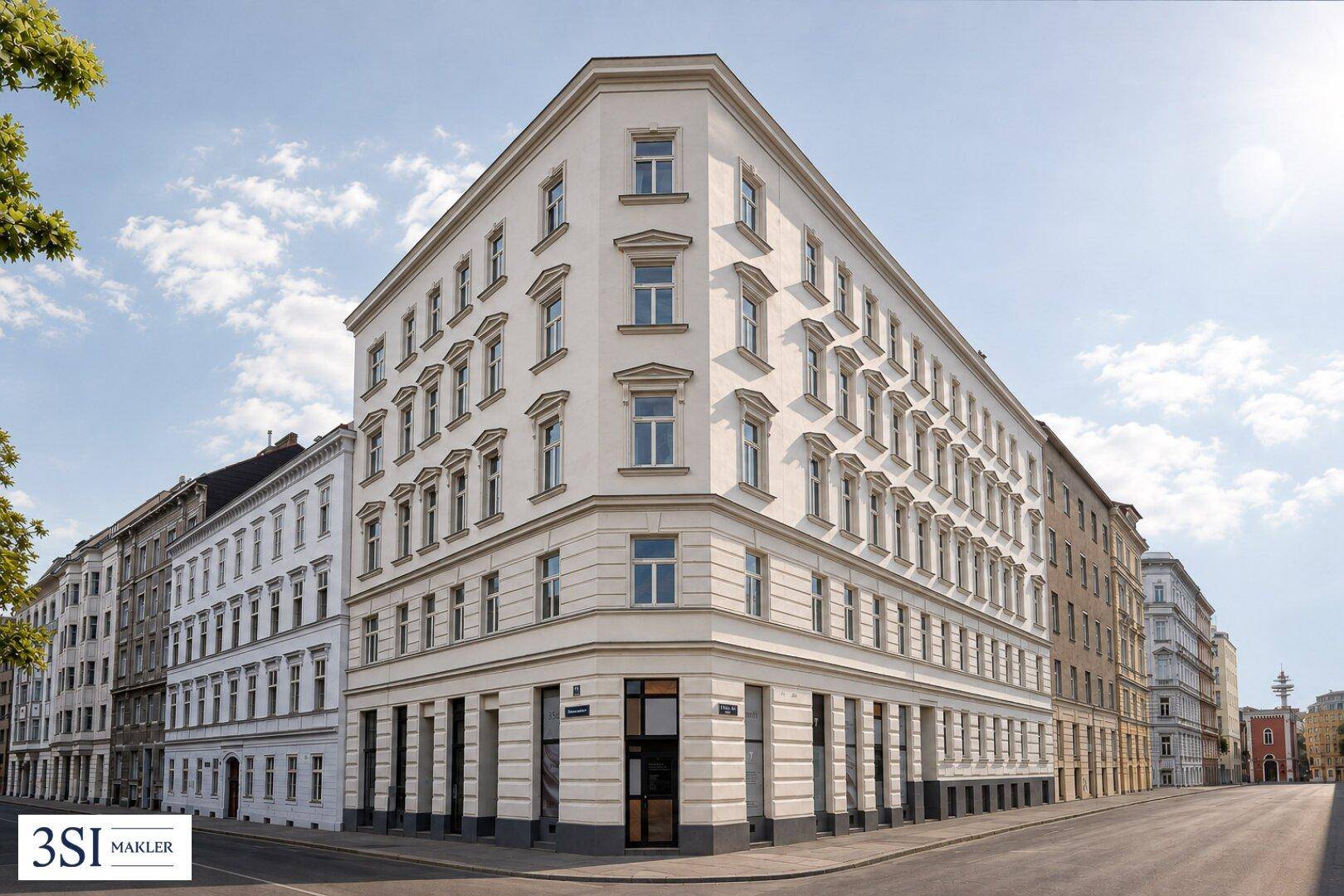 Elegantes Eckgebäude in der Stadt mit klassischer Architektur und vielen Fenstern unter blauem Himmel.
