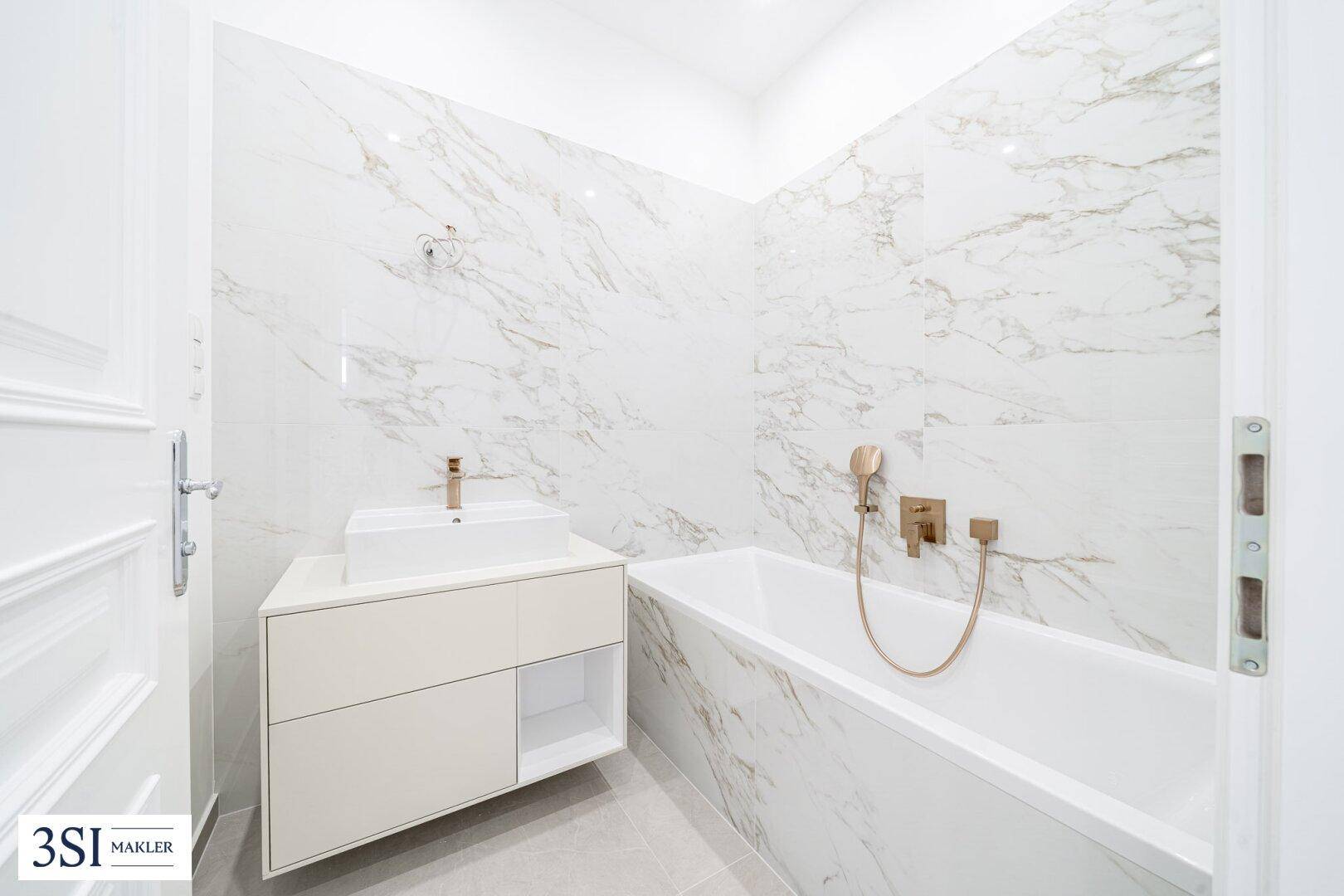 Elegantes Badezimmer mit Badewanne, modernem Waschtisch und Marmoroptik-Fliesen.
