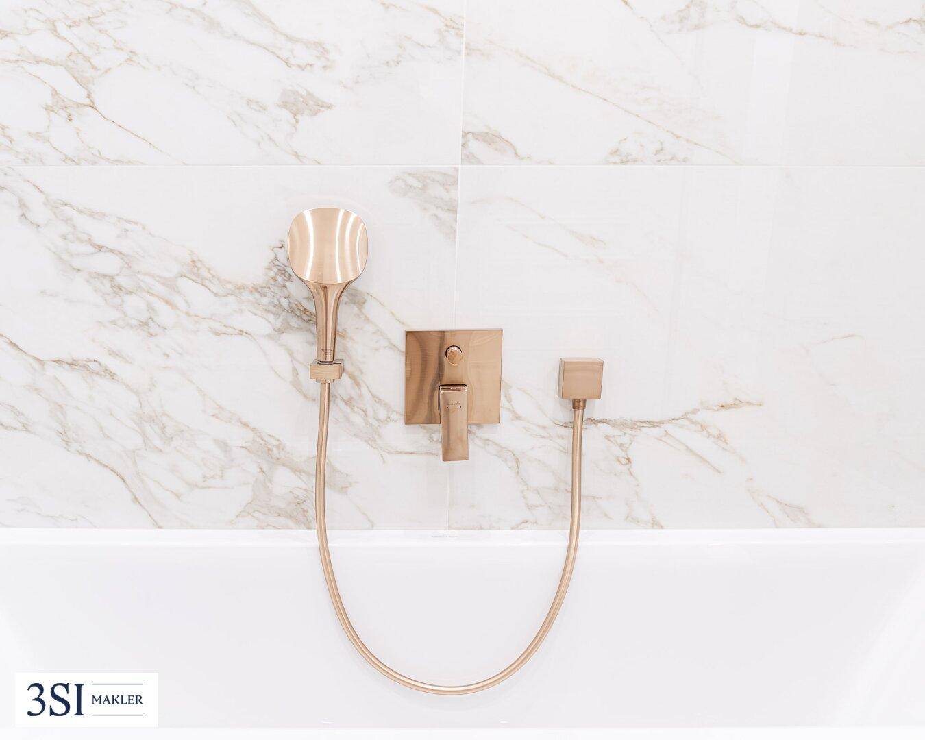 Detailaufnahme der modernen goldenen Armaturen in der Badewanne.